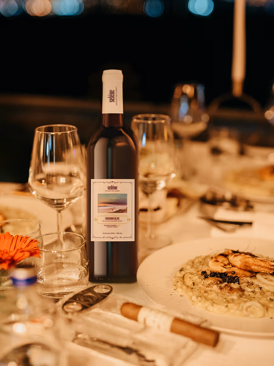 Bottle of Selēne Sauvignon Blanc wine on a table set with wine glasses and a seafood risotto dish.
