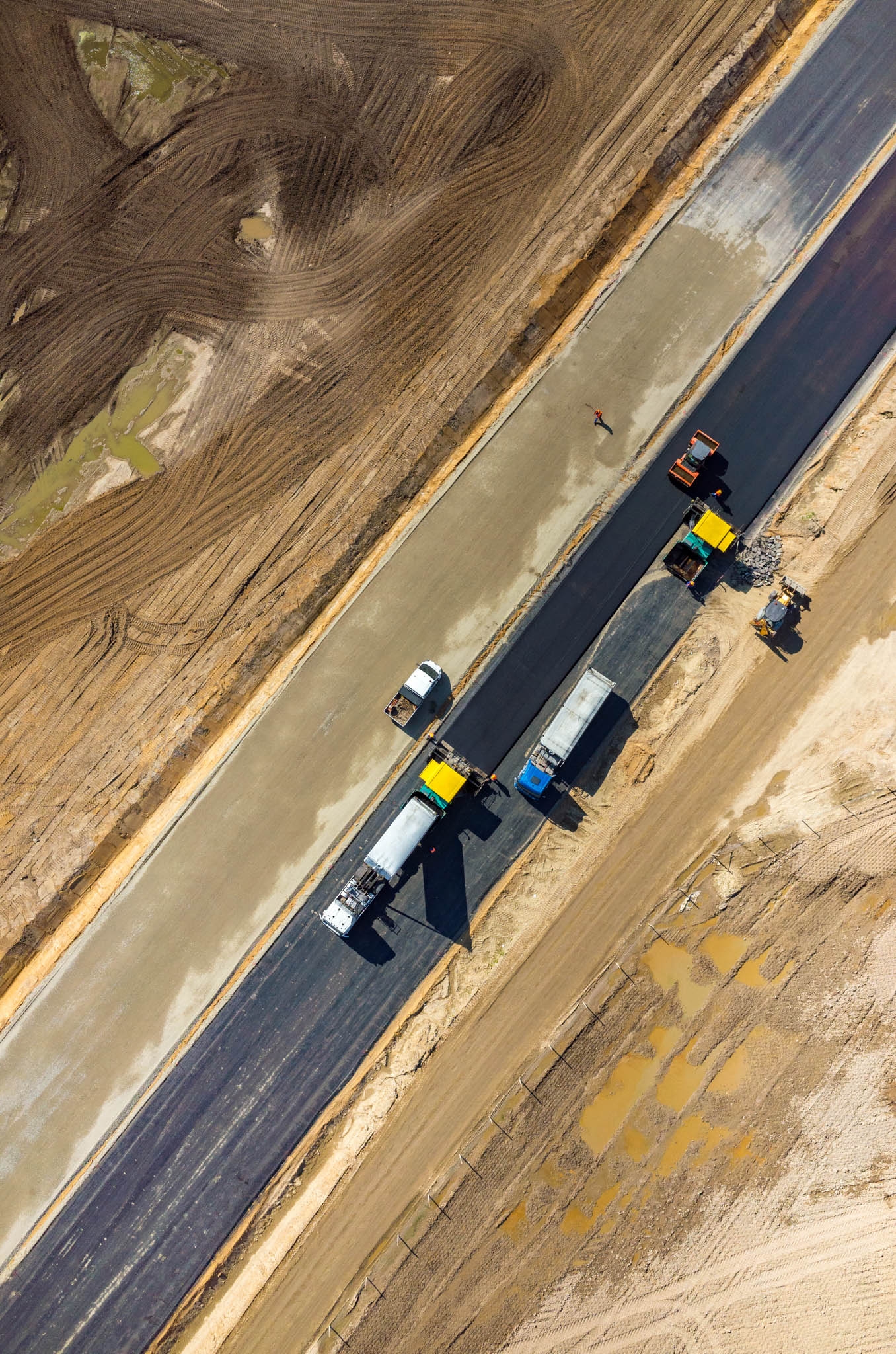 Construction vehicles paving a new road.