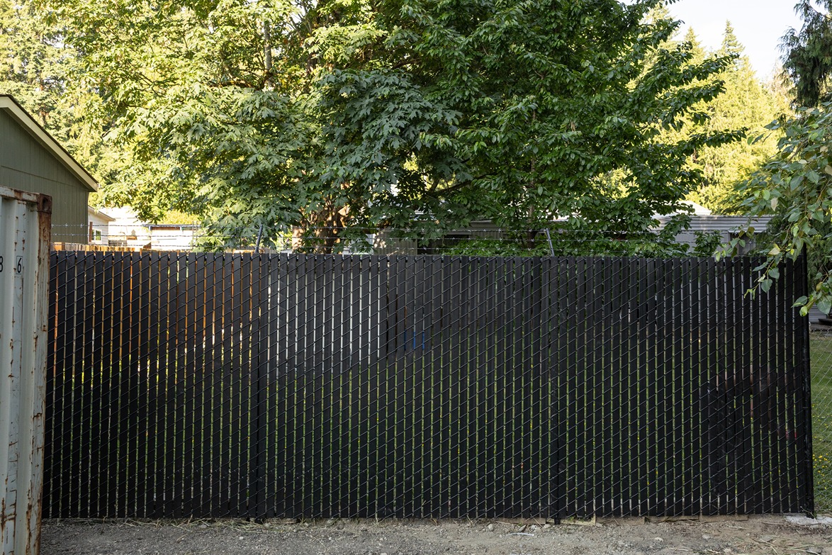 A chain-link fence with black privacy slats installed