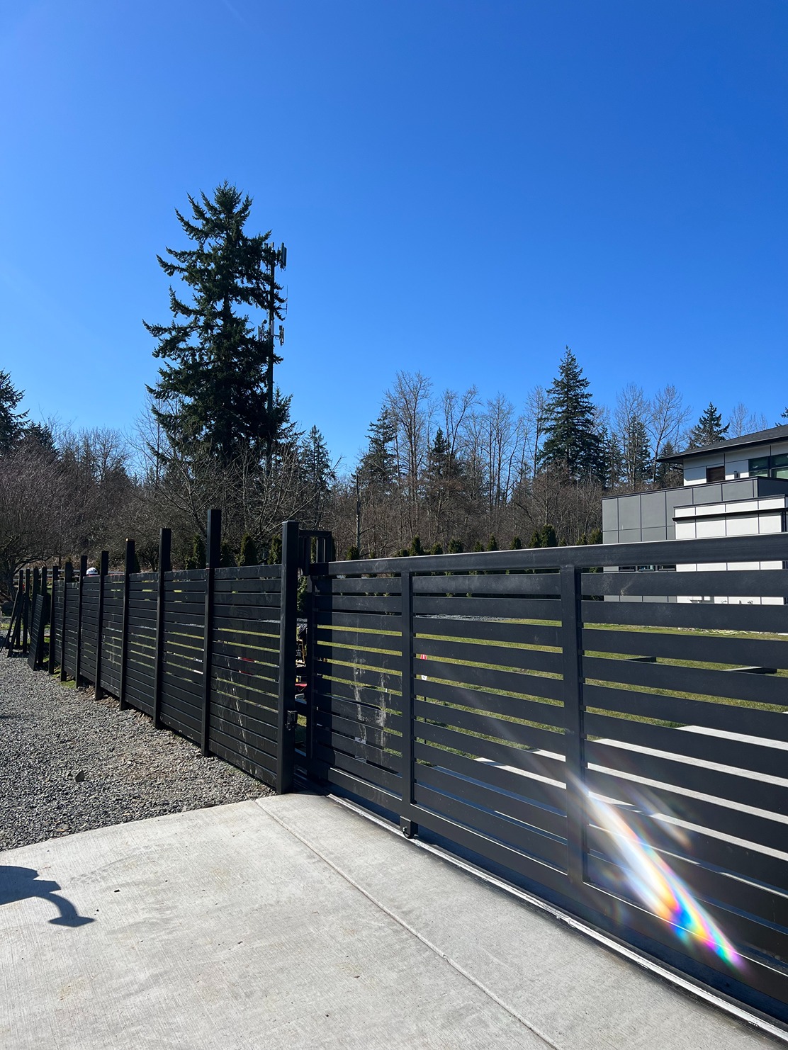 Modern horizontal slat metal fence with a sliding driveway gate