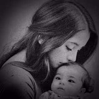 Black and white portrait of a young mother gently kissing her infant's forehead, capturing a moment of tender love and protection.