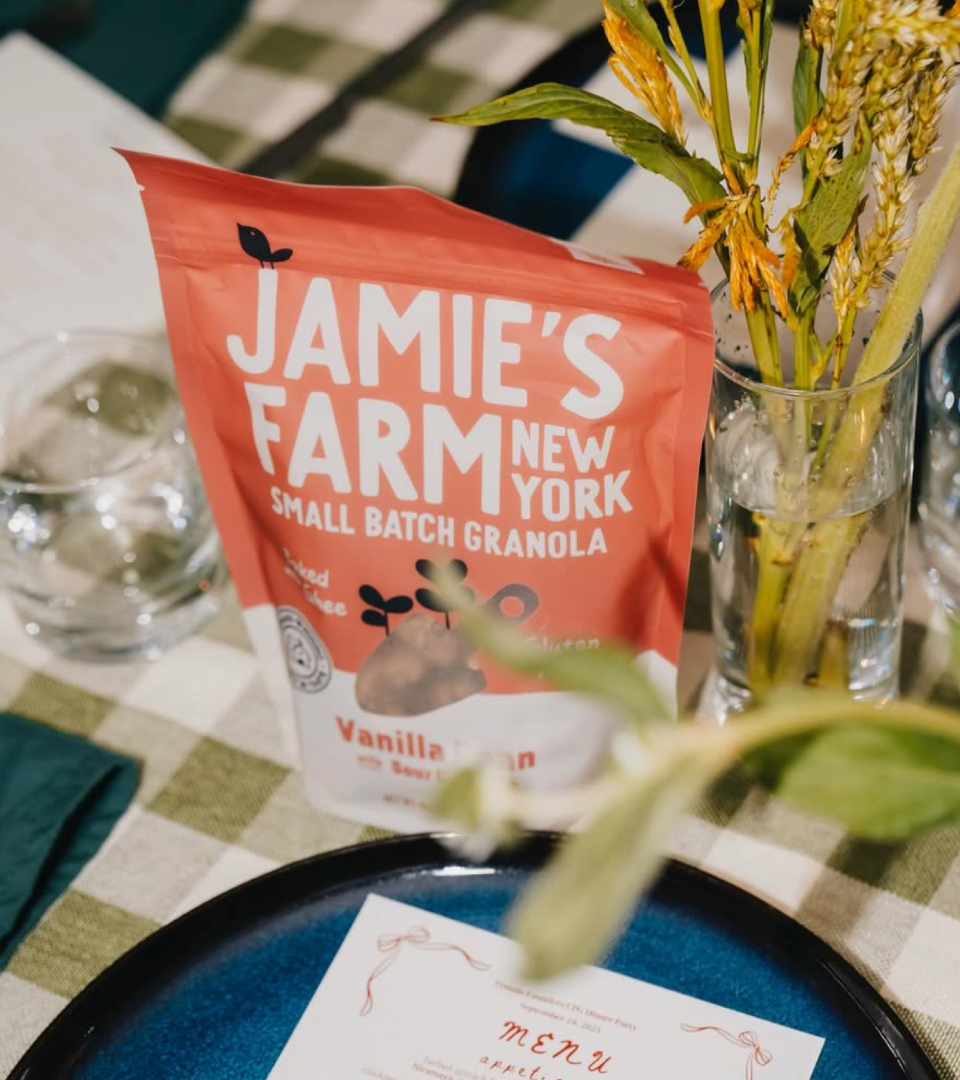 Jamie's Farm New York small batch granola bag displayed as a table centrepiece at a dinner party setting with dried grasses and a handwritten menu card