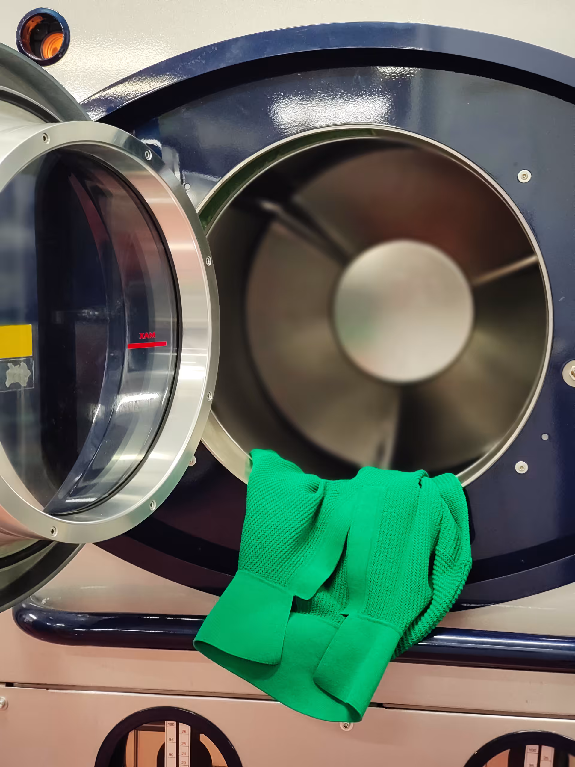 Maglia verde in lavatrice industriale – fase di lavaggio e finissaggio della maglieria nel ciclo produttivo interno di Max Company.