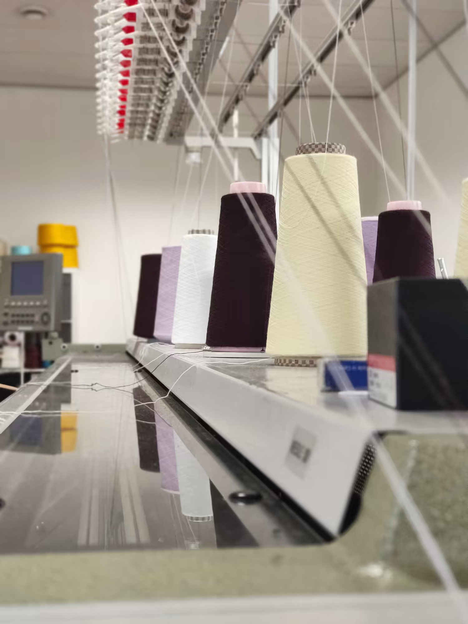 Rocche di filati colorati su macchina per maglieria Shima Seiki – produzione e tessitura di maglieria di lusso Made in Italy presso Max Company.