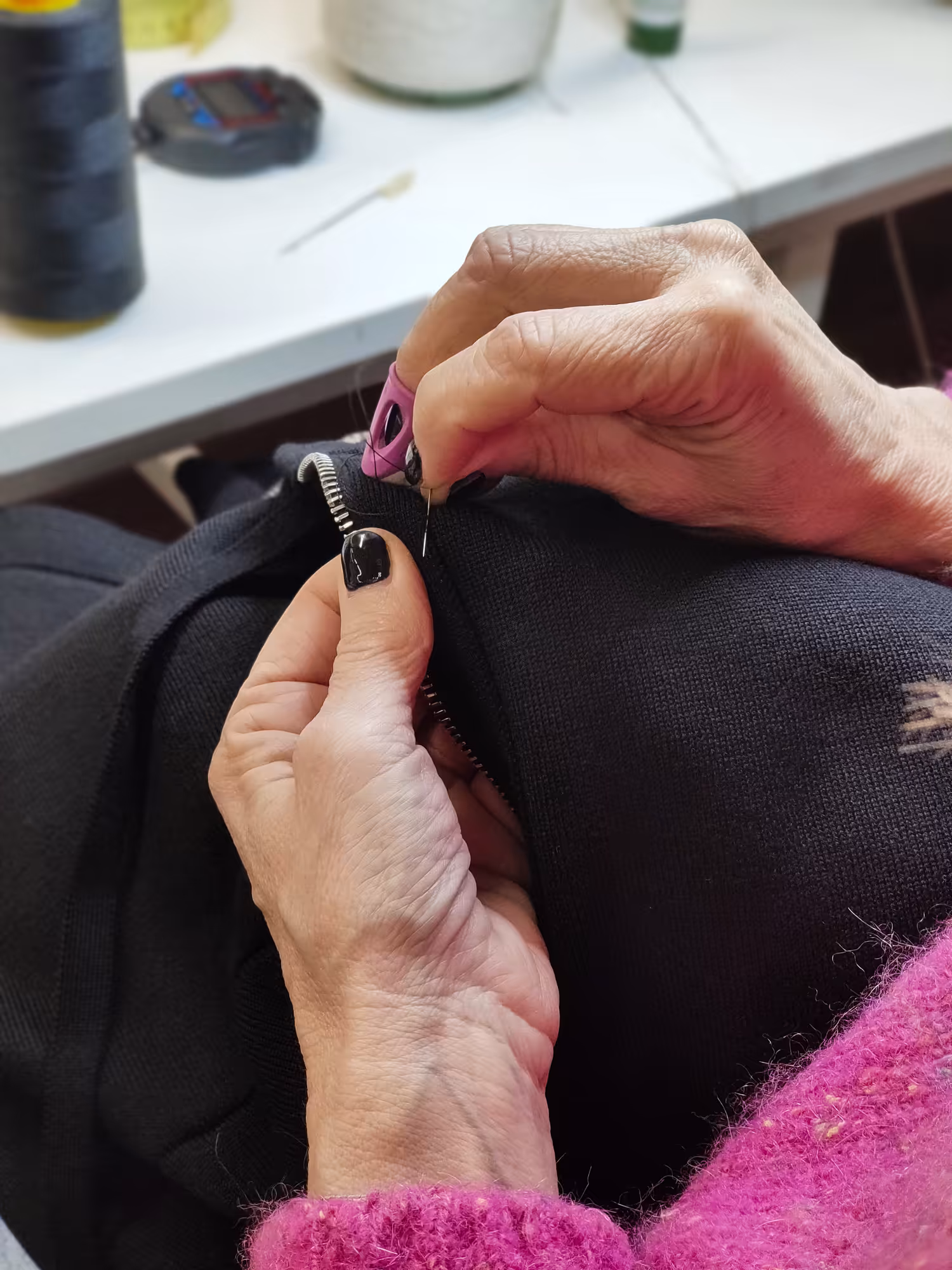 Rifinitura artigianale di un capo in maglia nera – cucitura a mano realizzata nel laboratorio Max Company.