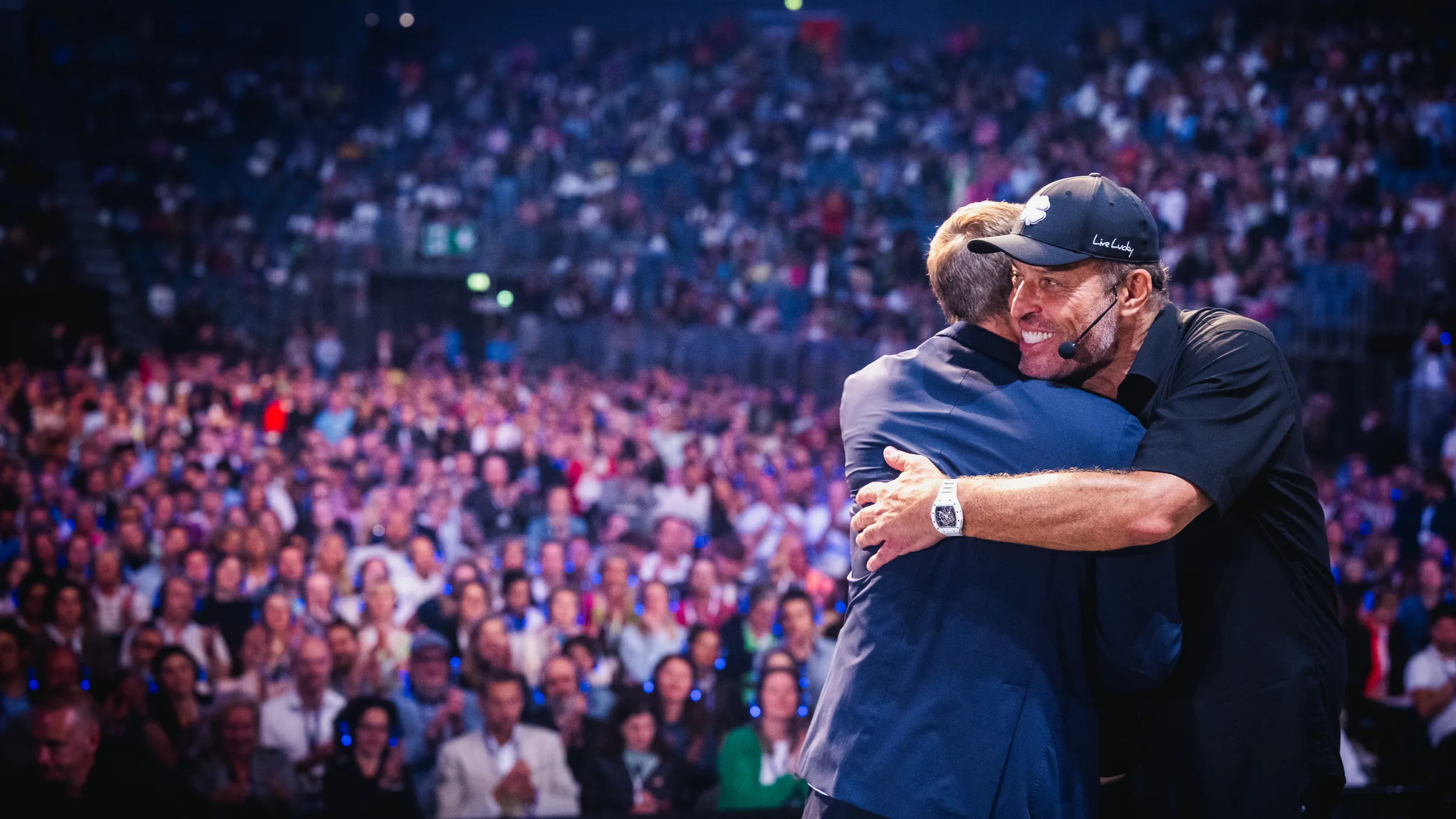 Tony Robbins umarmt Alexander Müller auf der Bühne vor Tausenden Menschen