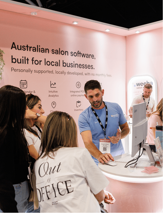 Weeha team member in a blue shirt chatting with visitors at the Weeha stand