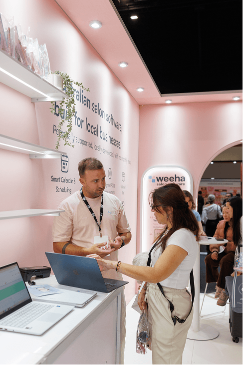Weeha team member showing a salon owner the Weeha software on a laptop