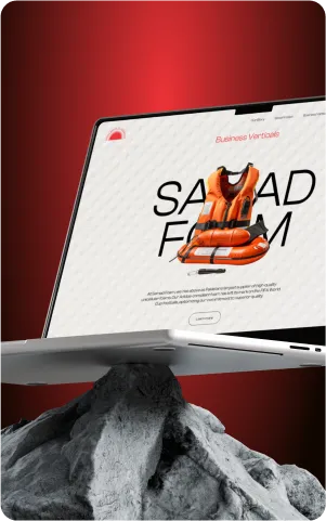 Laptop displaying a website with an orange life vest on a rocky surface, against a red background.