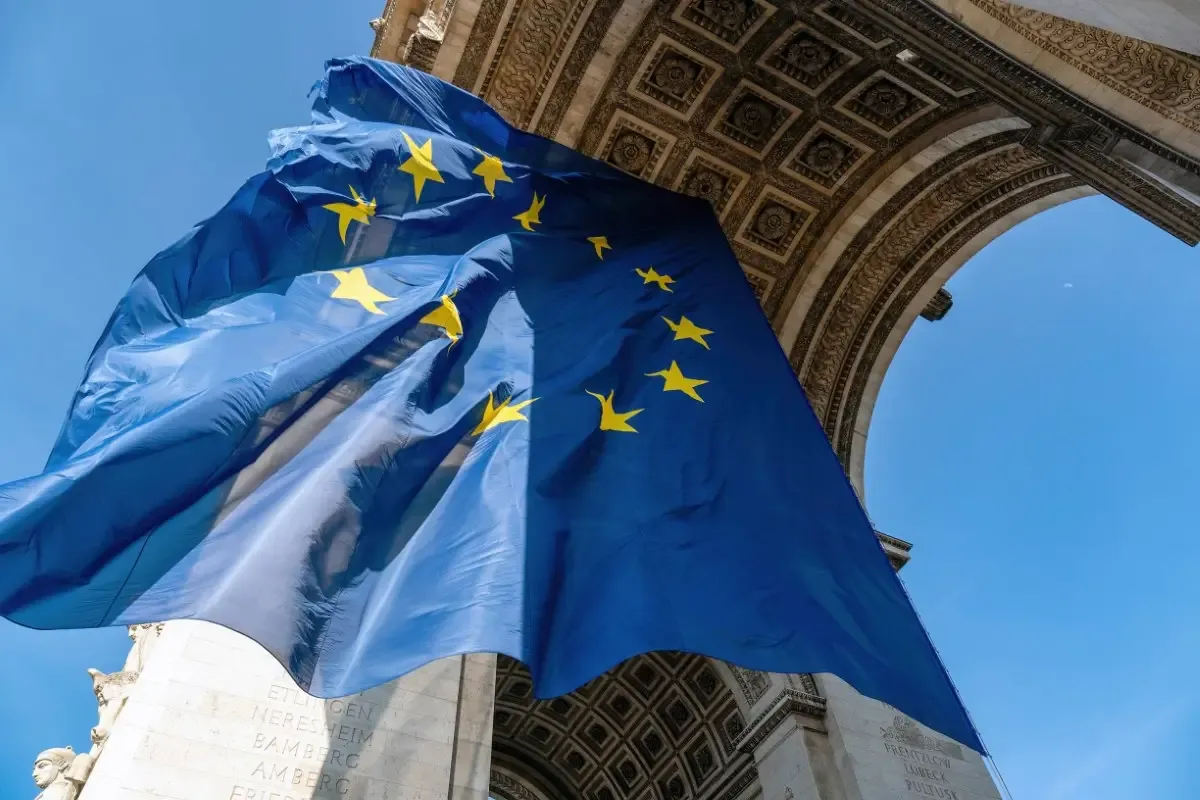 A european flag flying in front of a stone arch