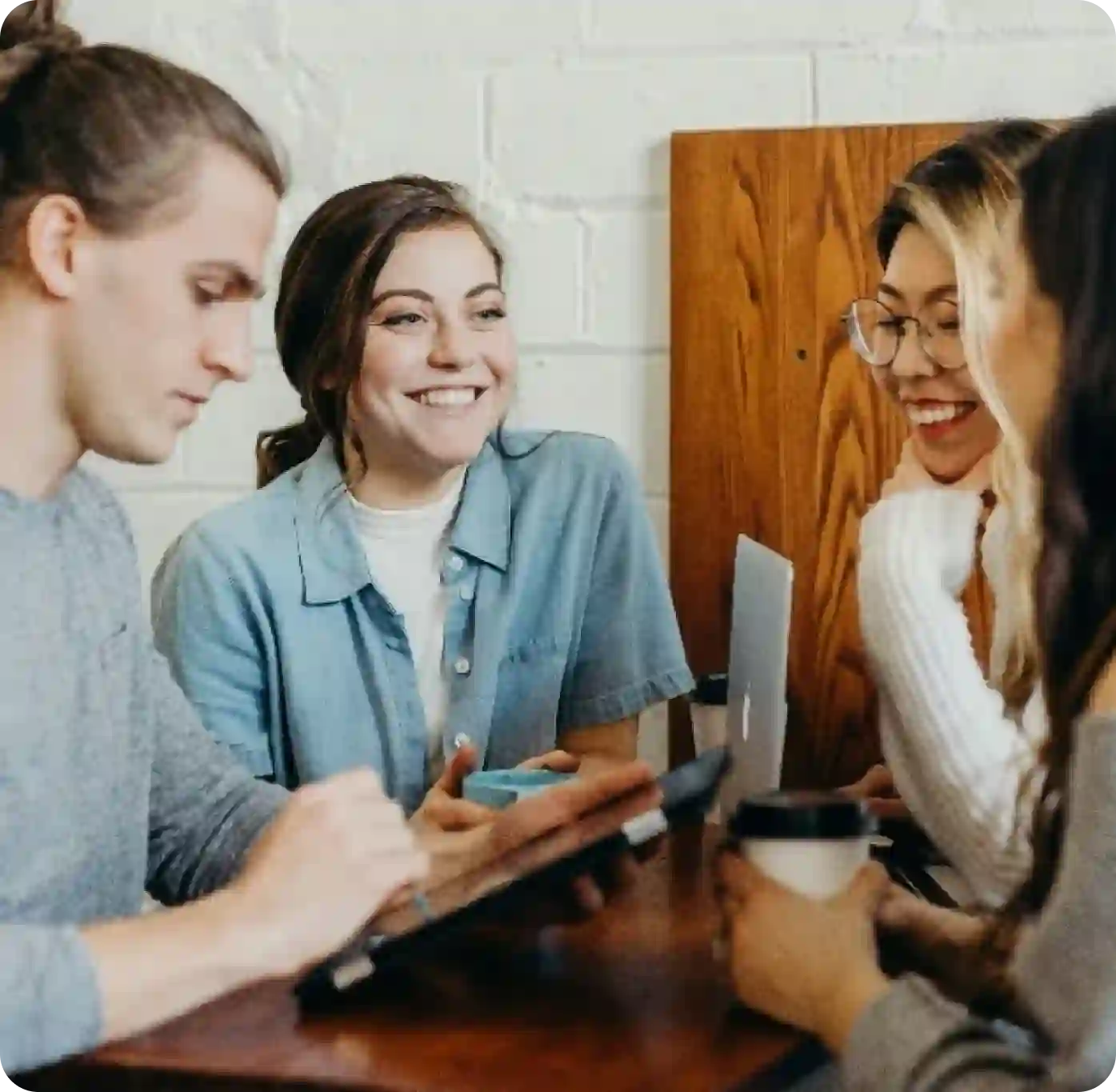 A group of people sitting around a wooden table.