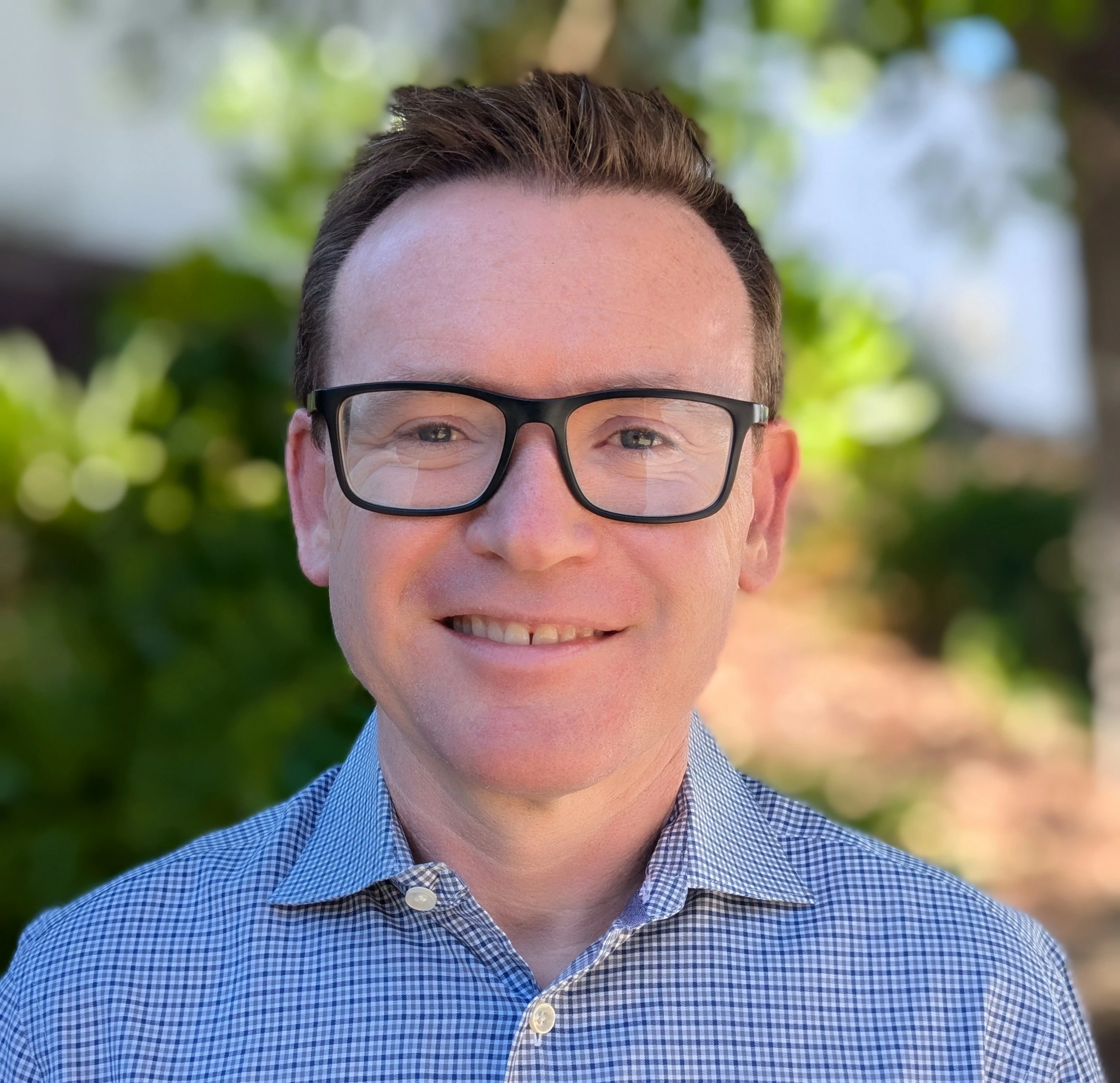 An Image of Thomas Larkin wearing a blue shirt and glasses