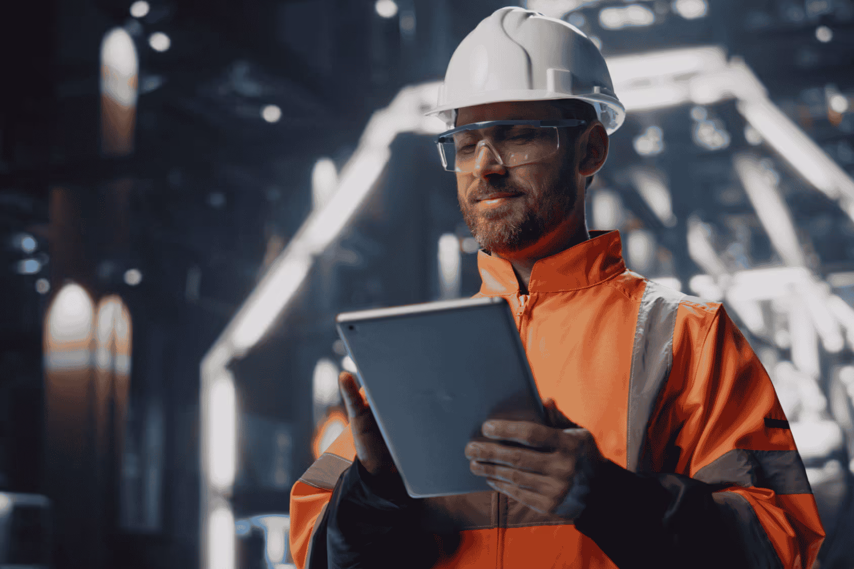 Two engineers in industrial or warehouse facility looking down at a tablet.