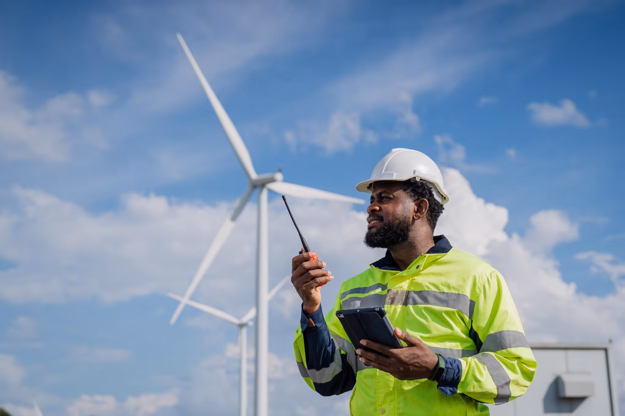 Electrical engineer on the job with wind turbine in the background