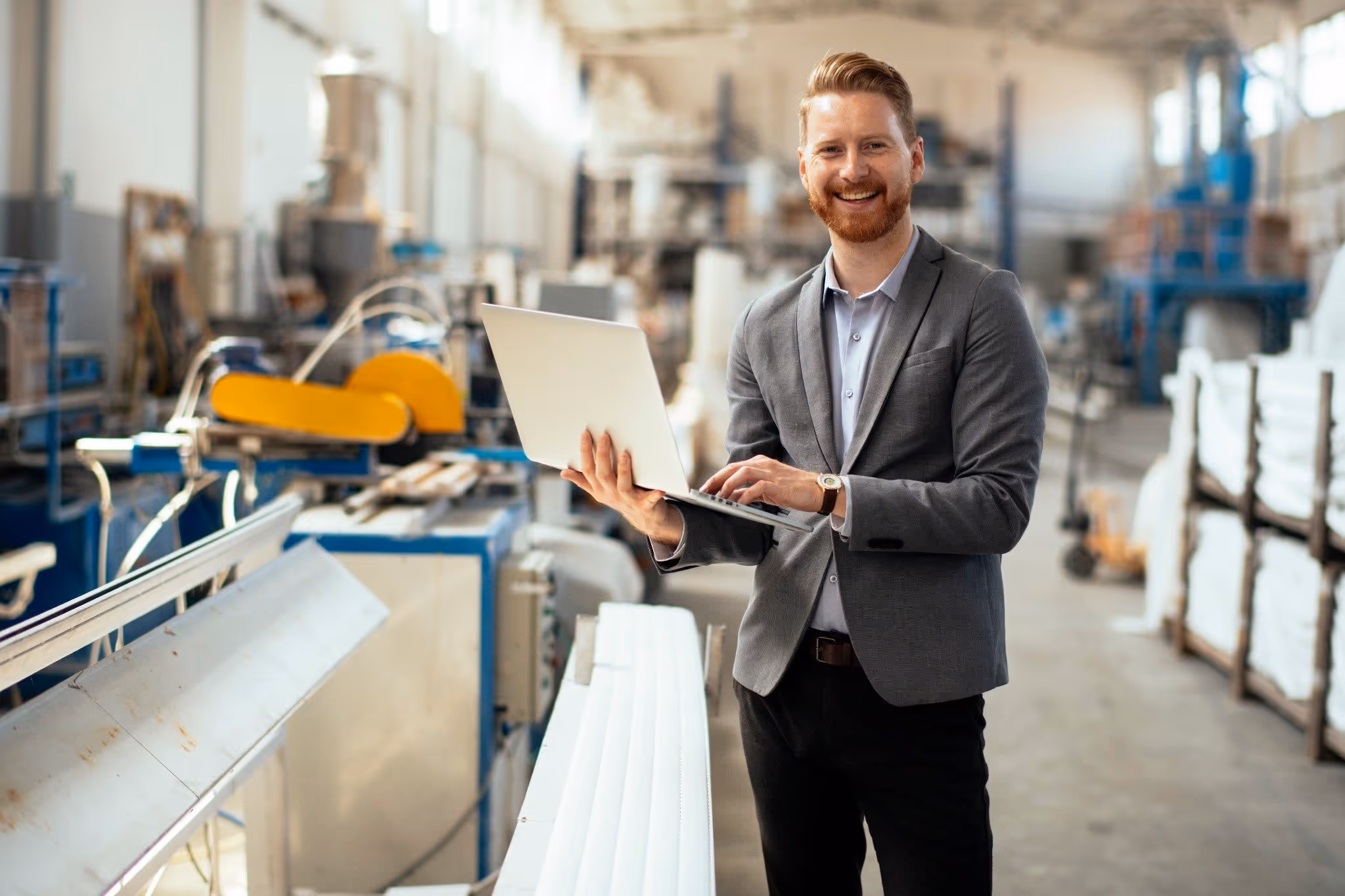 Factory manager conducting inspection and recording results on a laptop
