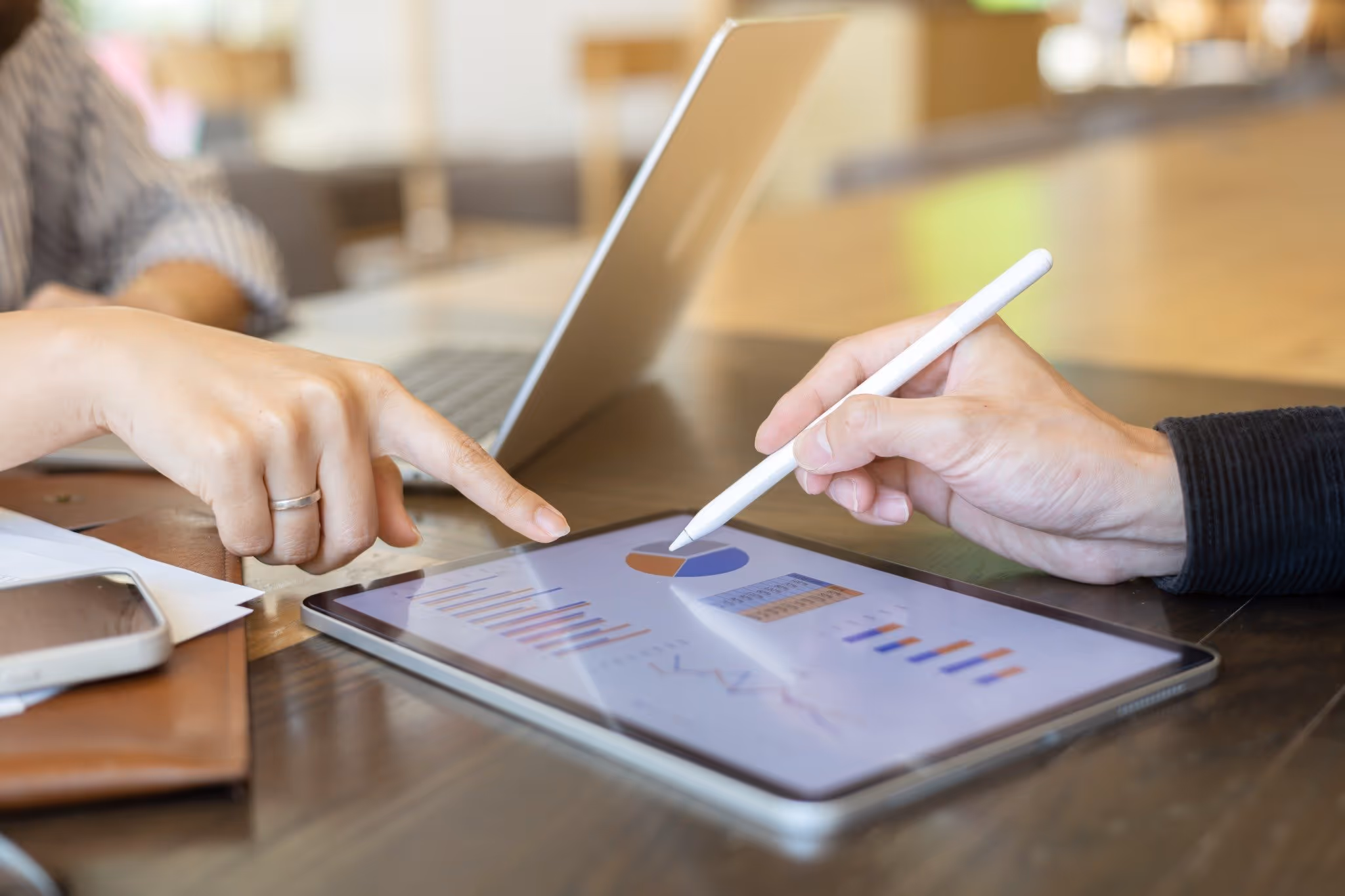 two people looking at data and graphs on a tablet screen