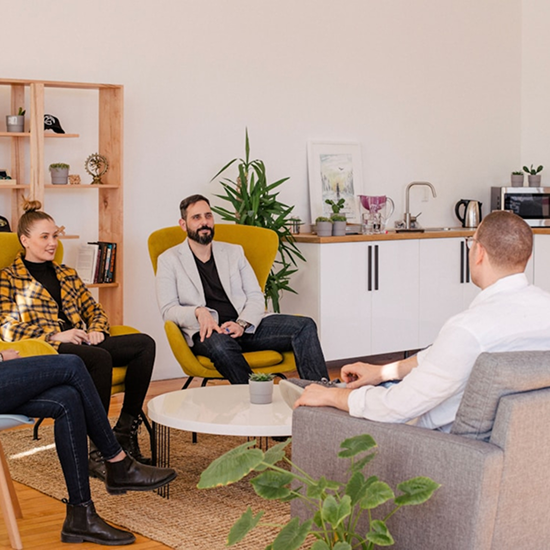 Ein entspanntes Team-Meeting in einer modernen, einladenden Umgebung mit stilvollen Möbeln und Pflanzen. Symbolisiert die kreative Zusammenarbeit und den strategischen Ansatz hinter der Fallstudie für Adidas.