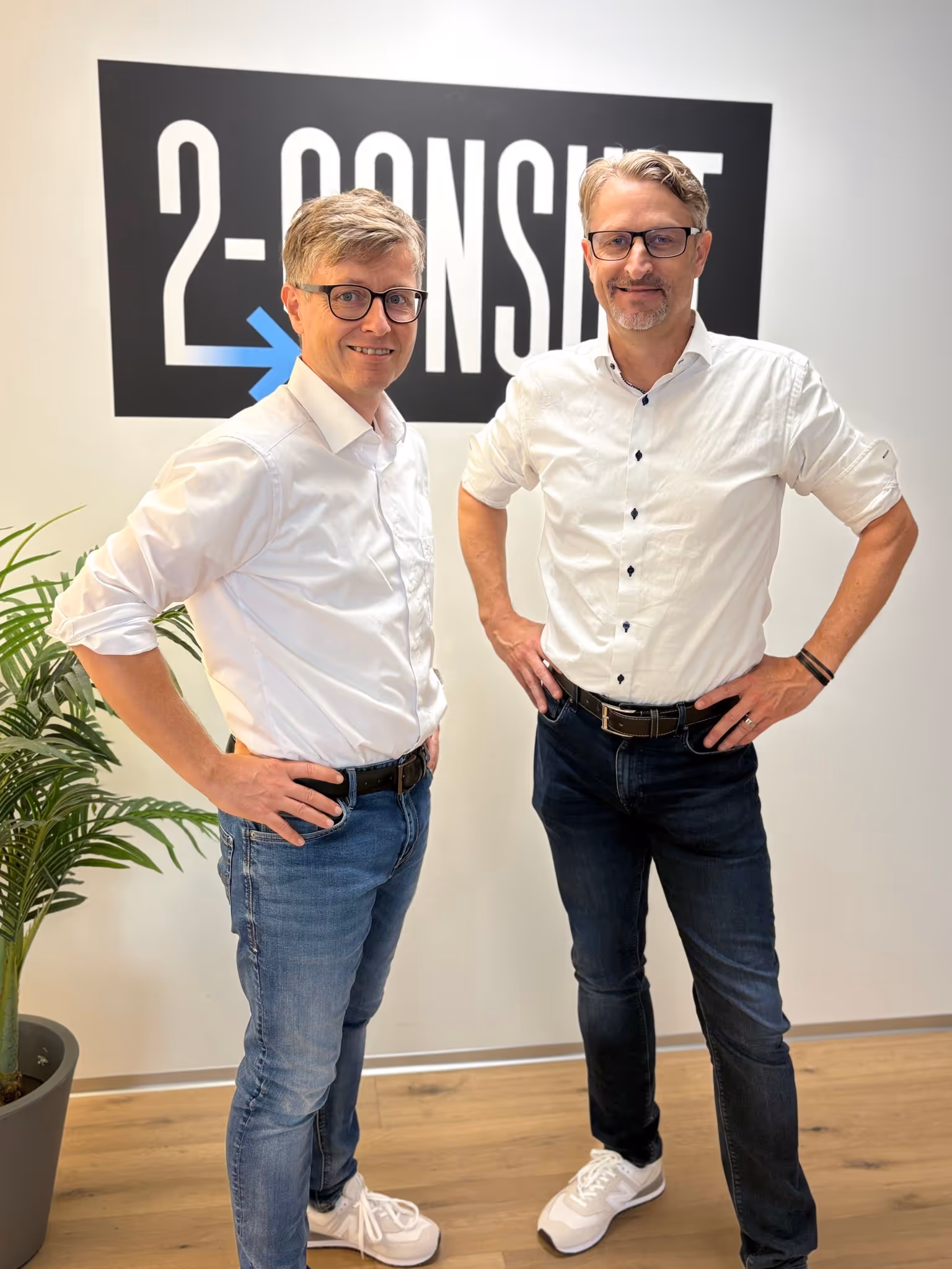 Andreas Signer und André Burkart stehen vor dem 2-Consult Logo