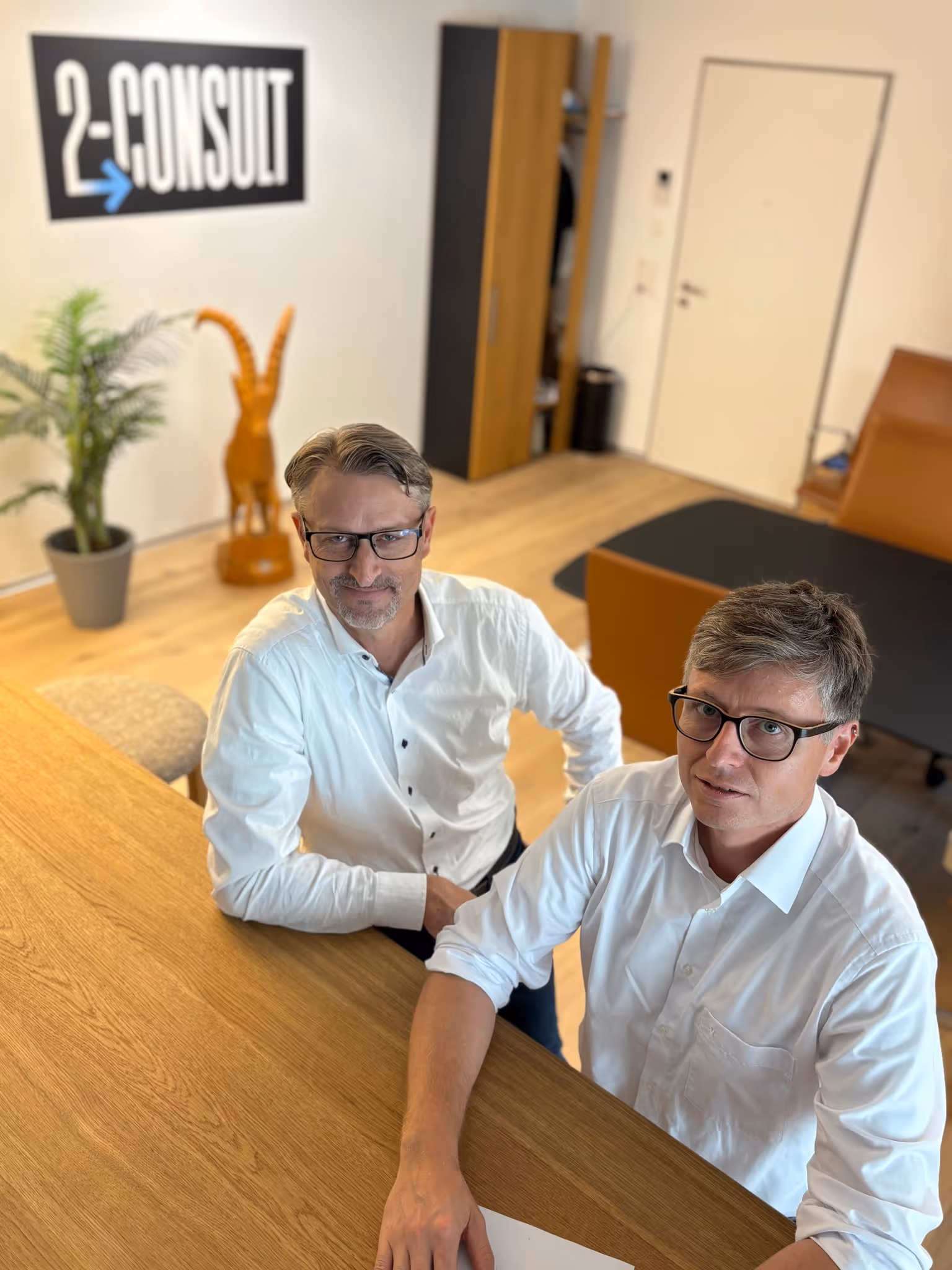 André Burkart und Andreas Signer sitzen an einem Holztisch