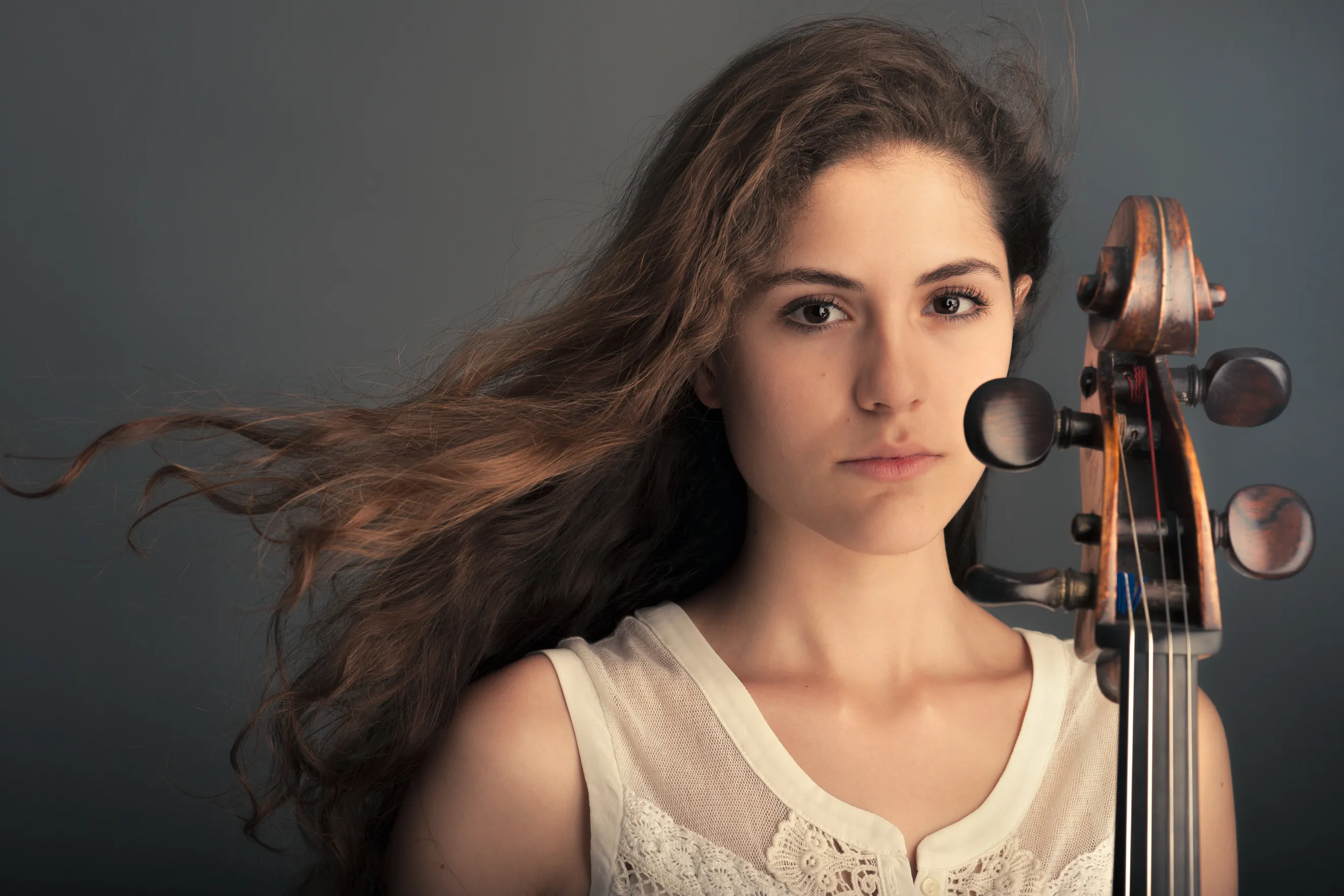 צילום מוזיקאים מקצועי לצרכי קידום של מוזיקאית עם צ'לו בסטודיו במרכז הארץ עם תאורה דרמטית ומחמיאה.