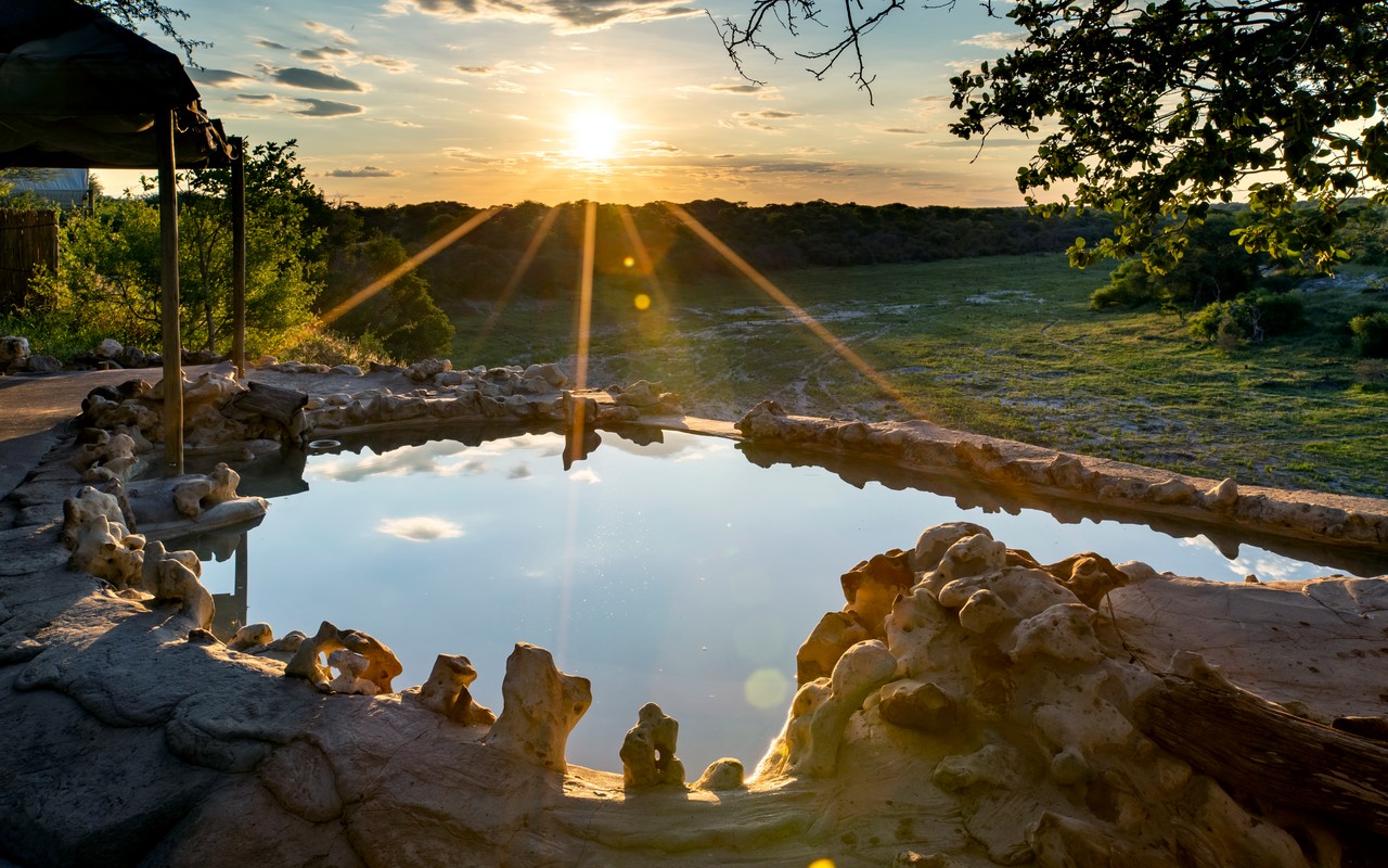 Cliff-edge pool with panoramic views of the Boteti River and wildlife below.