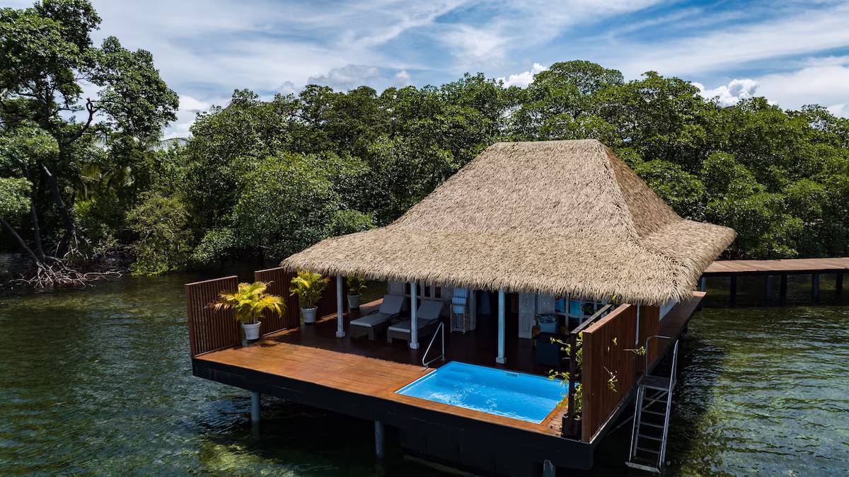 Private villas suspended above crystal-clear Caribbean waters with immersive indoor-outdoor living.
