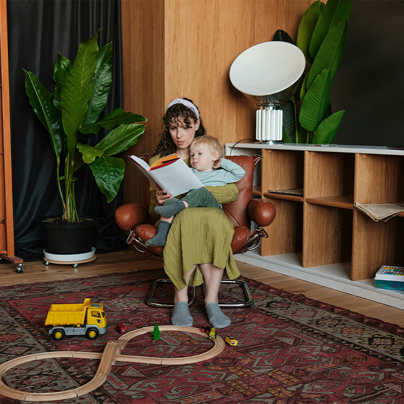 Woman sitting in a brown chair reading a book to a child. Clean Slate Clinic client.
