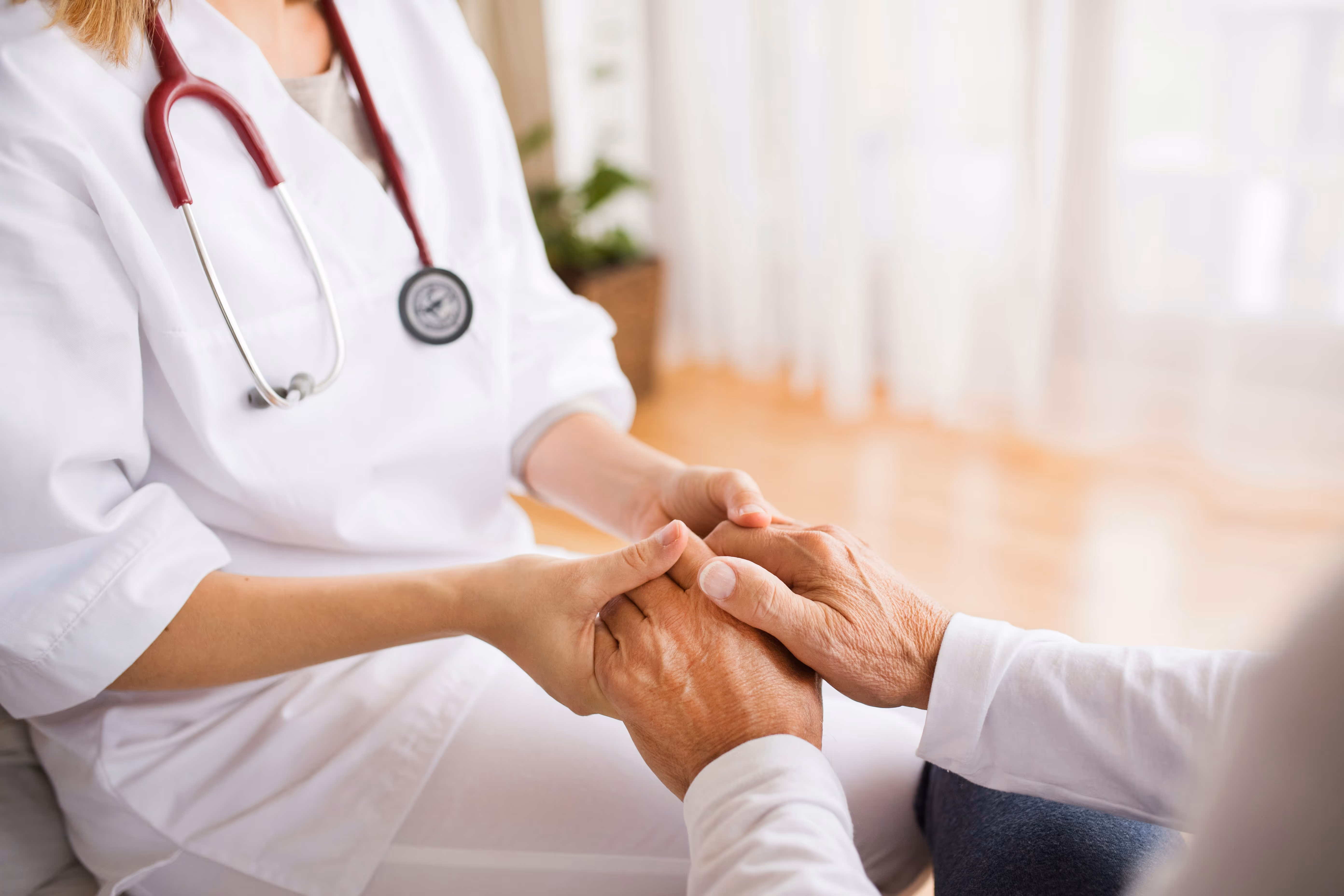 Healthcare professional gently holding the hands of an elderly person in a warm, supportive gesture.