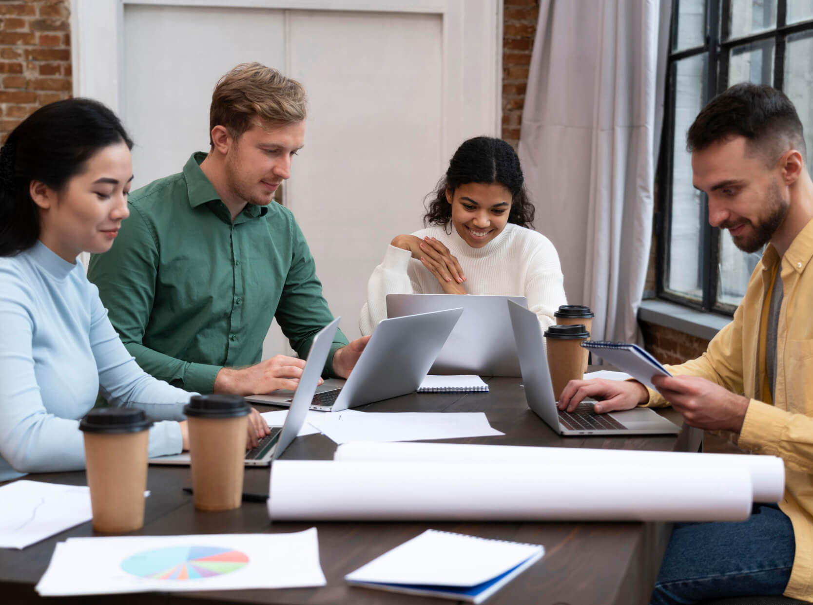A group of people sitting around a table working on laptops.