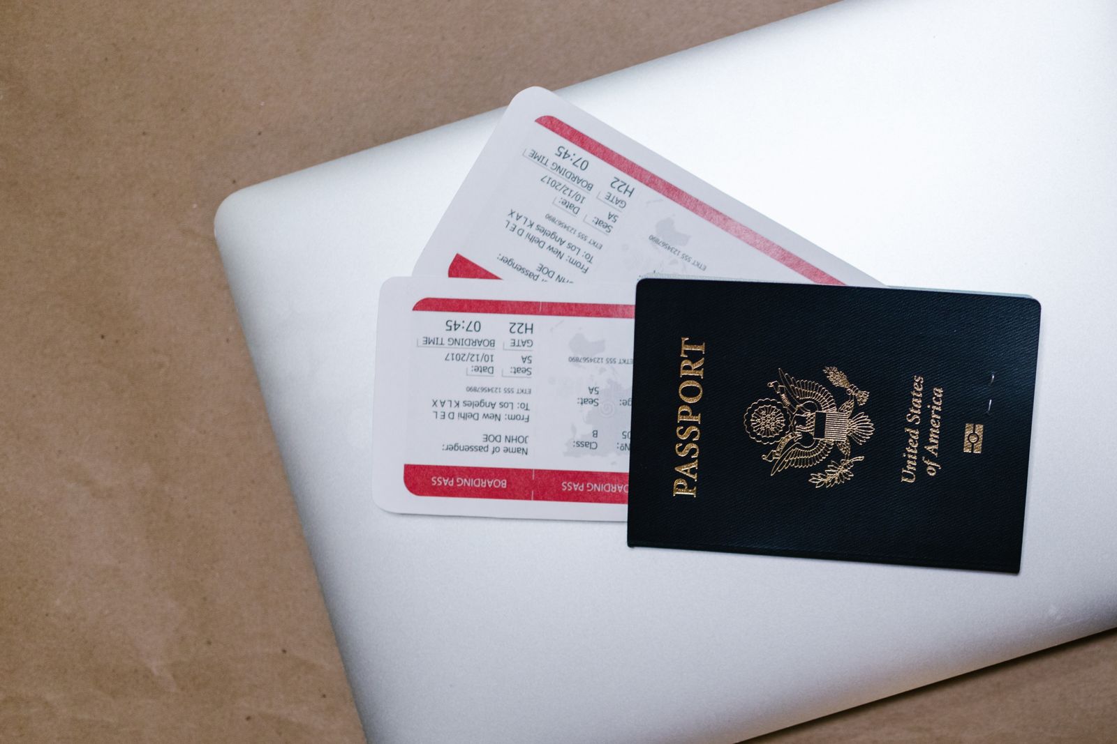 A passport and boarding passes resting on a laptop