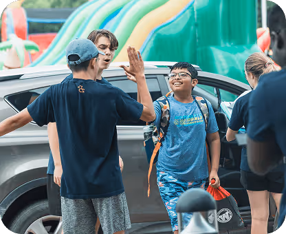 Camp directors and children high five