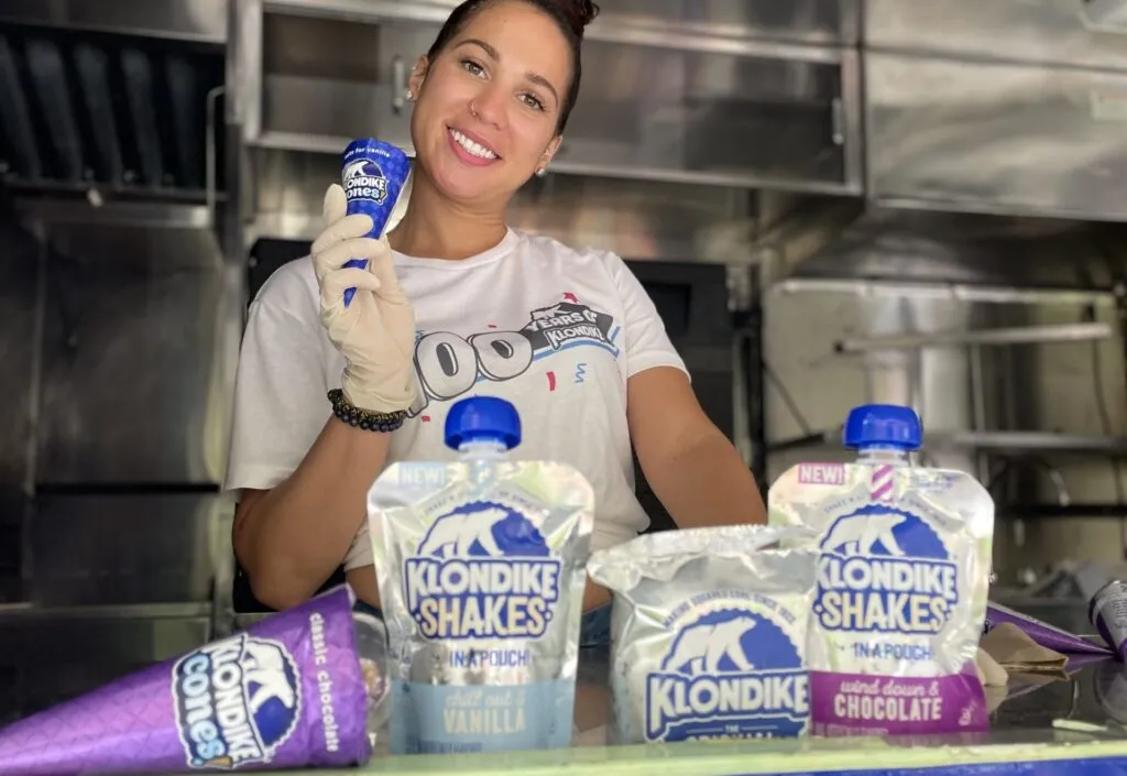 Staff member holding a drink pouch behind a counter of Klondike Shakes samples