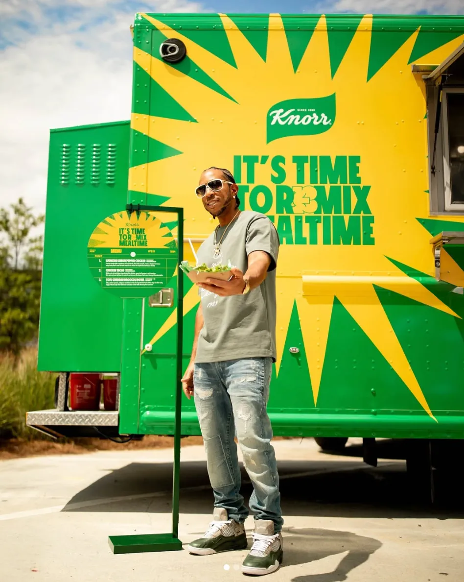 Man standing beside a green and yellow Knorr branded truck with a starburst graphic