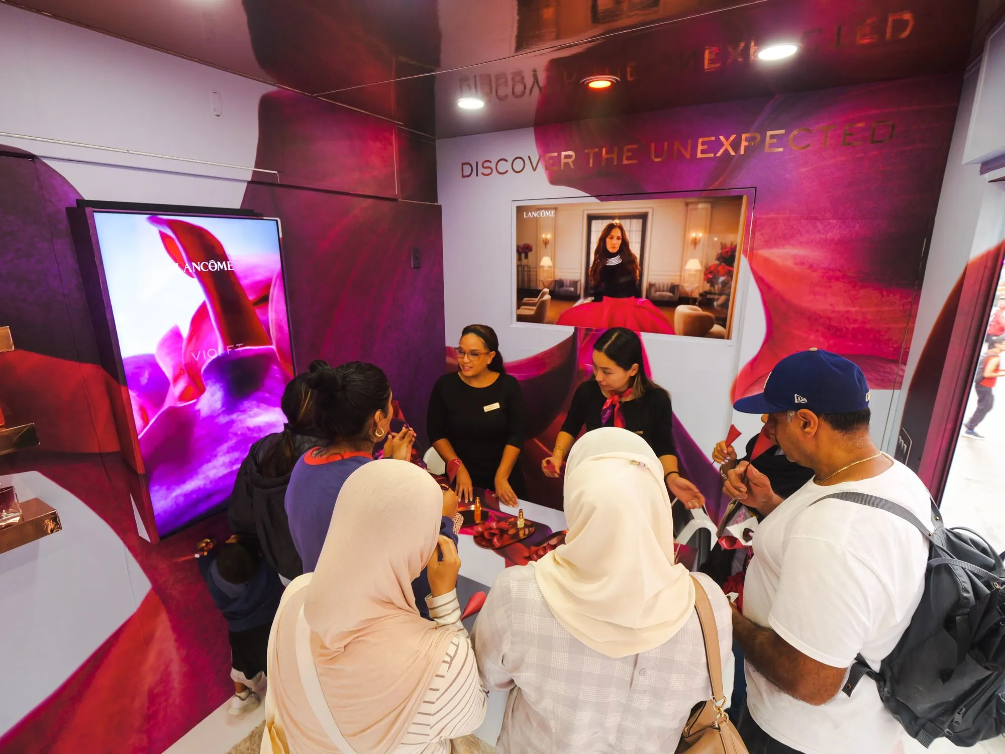 Visitors gathered around a lit product display inside a dark branded immersive room