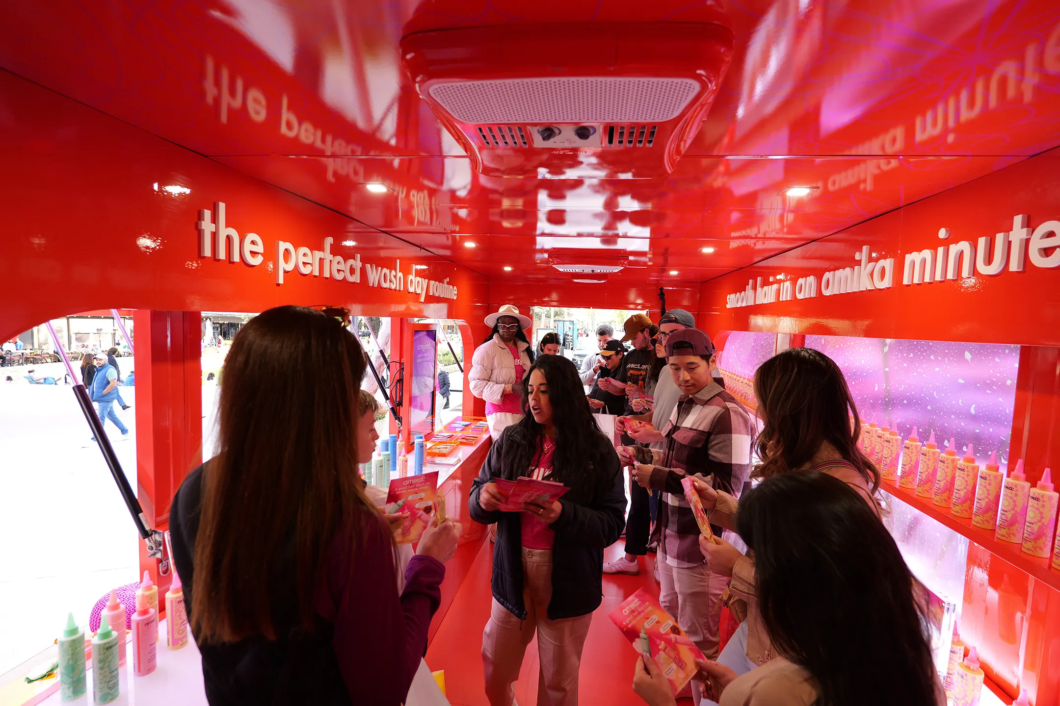 Guests collecting samples inside a bright red amika mobile experience trailer