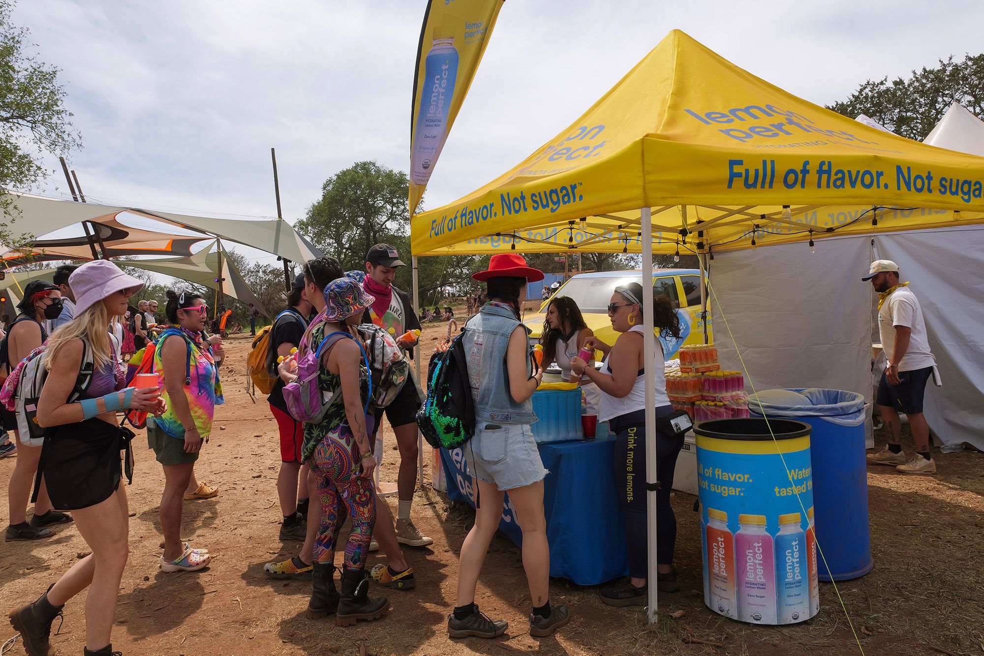 Festival crowd queuing at a yellow sampling tent with Lemon Perfect branded coolers