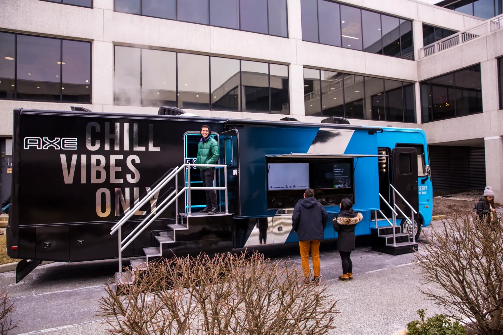 Black and blue AXE branded tour trailer with steps down to an outdoor plaza