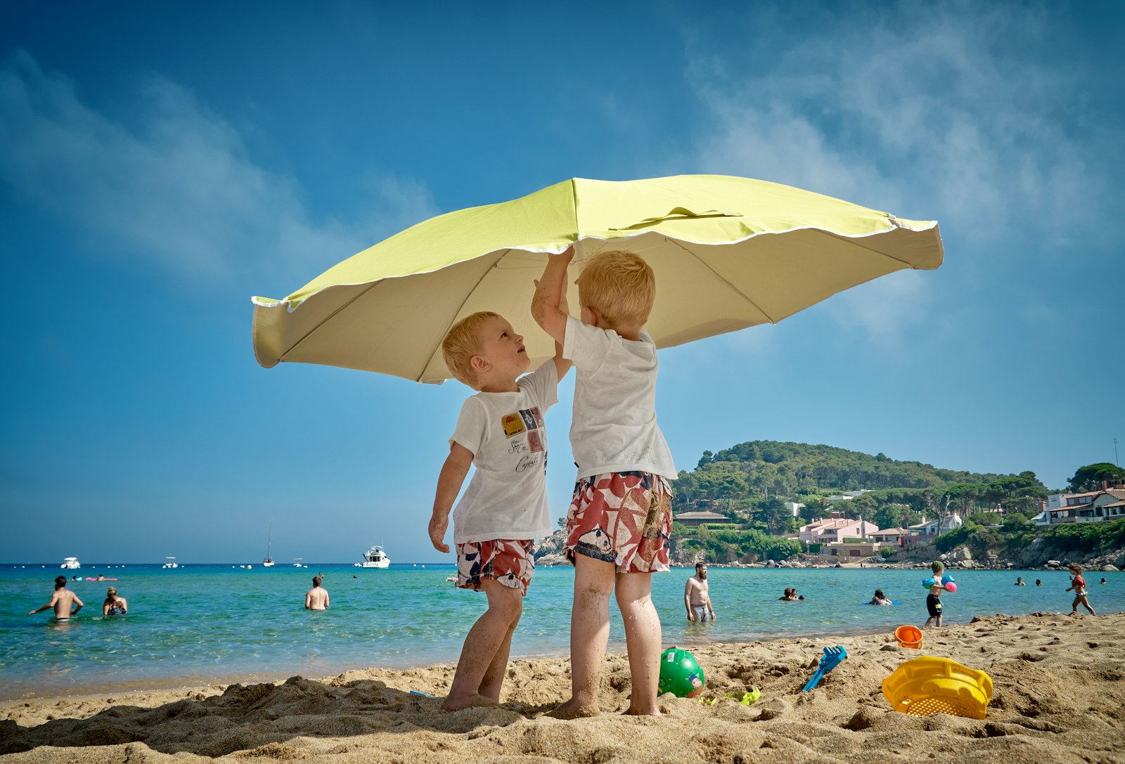 Children playing under a beach umbrella on a Mediterranean Costa Blanca beach