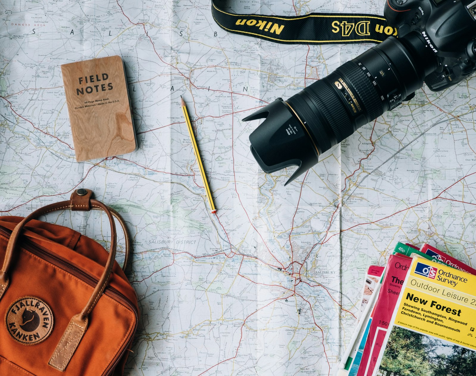 Travel planning flatlay with map, camera and notebook on a wooden table