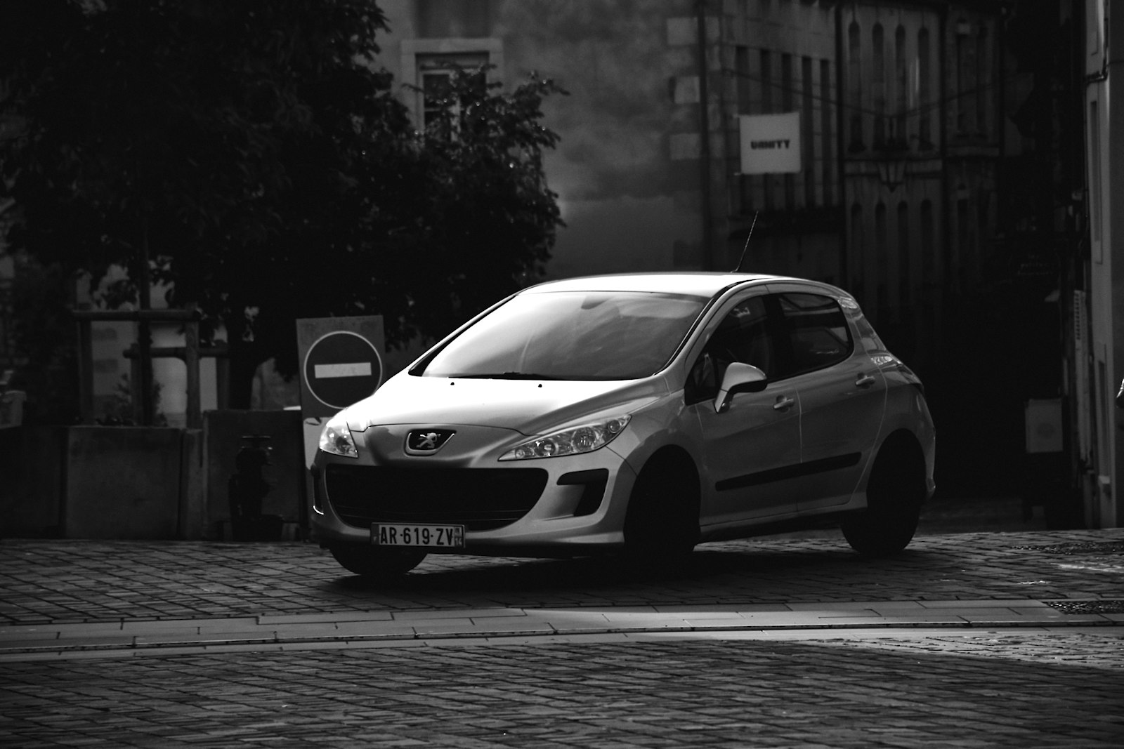 Peugeot 308 compacto aparcado en calle empedrada europea, flota de coches modernos WeOneRent Alicante