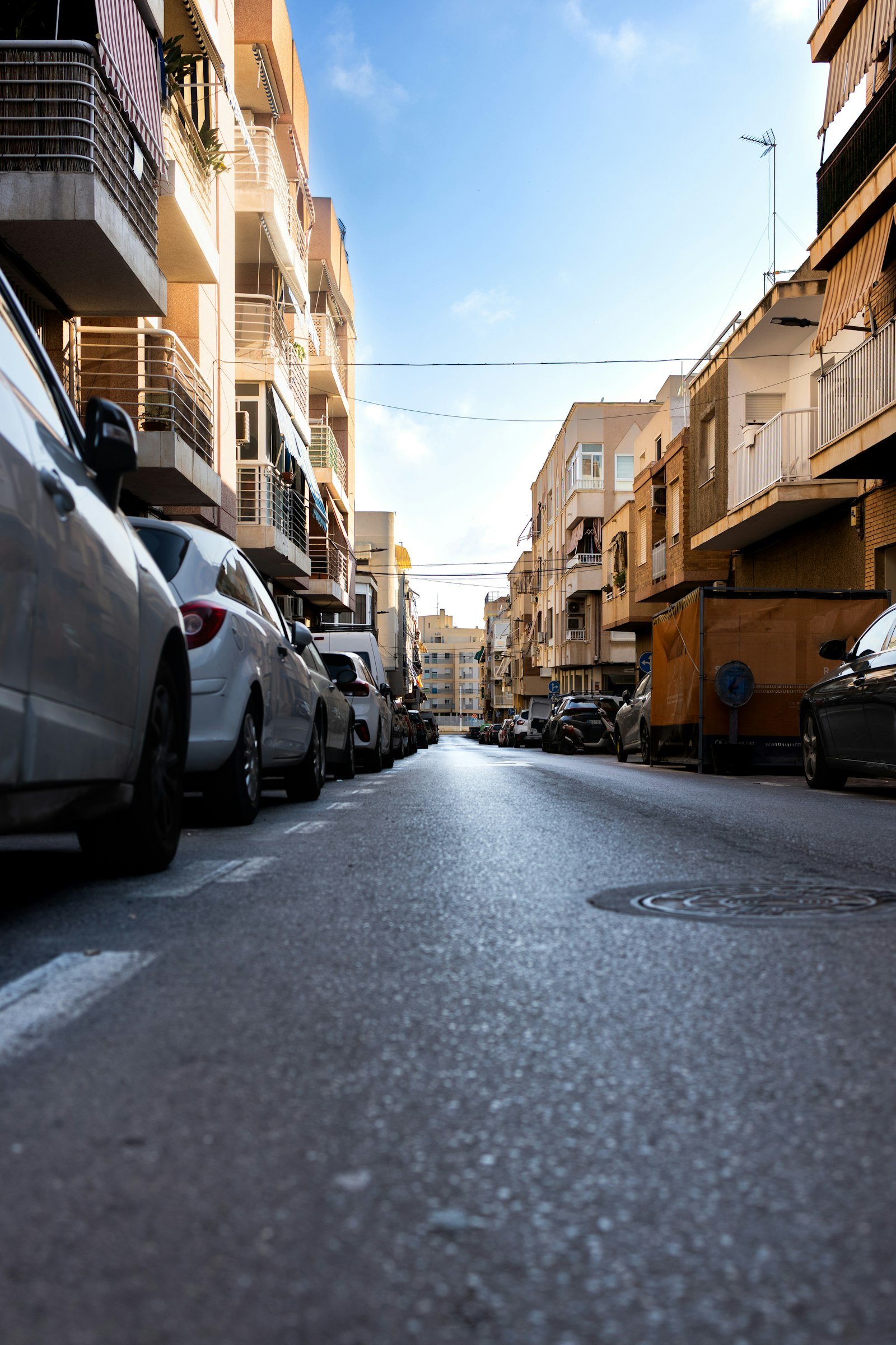 Rue résidentielle ensoleillée d'Alicante avec voitures garées et immeubles d'appartements méditerranéens