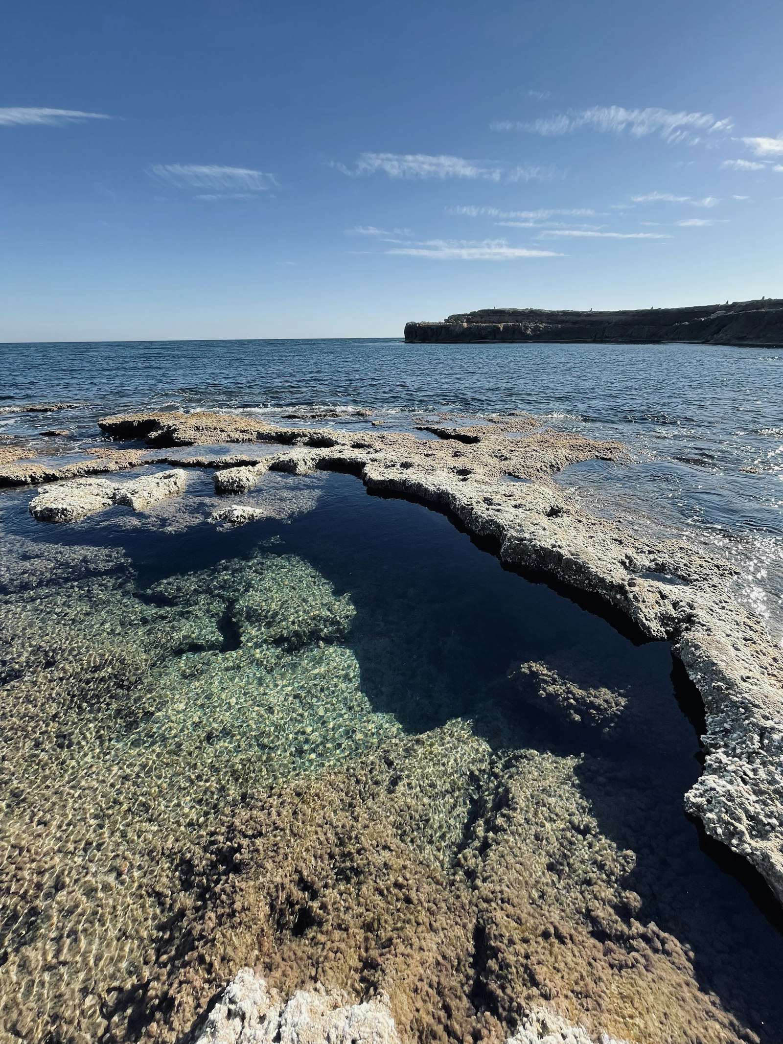 Rocky Mediterranean coastline with crystal clear tidal pools near Torrevieja, Spain, with limestone cliffs and blue sea