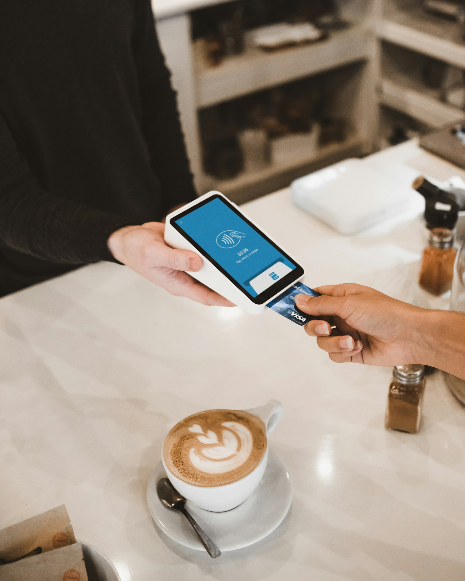 Person paying with a Visa card at a contactless payment terminal