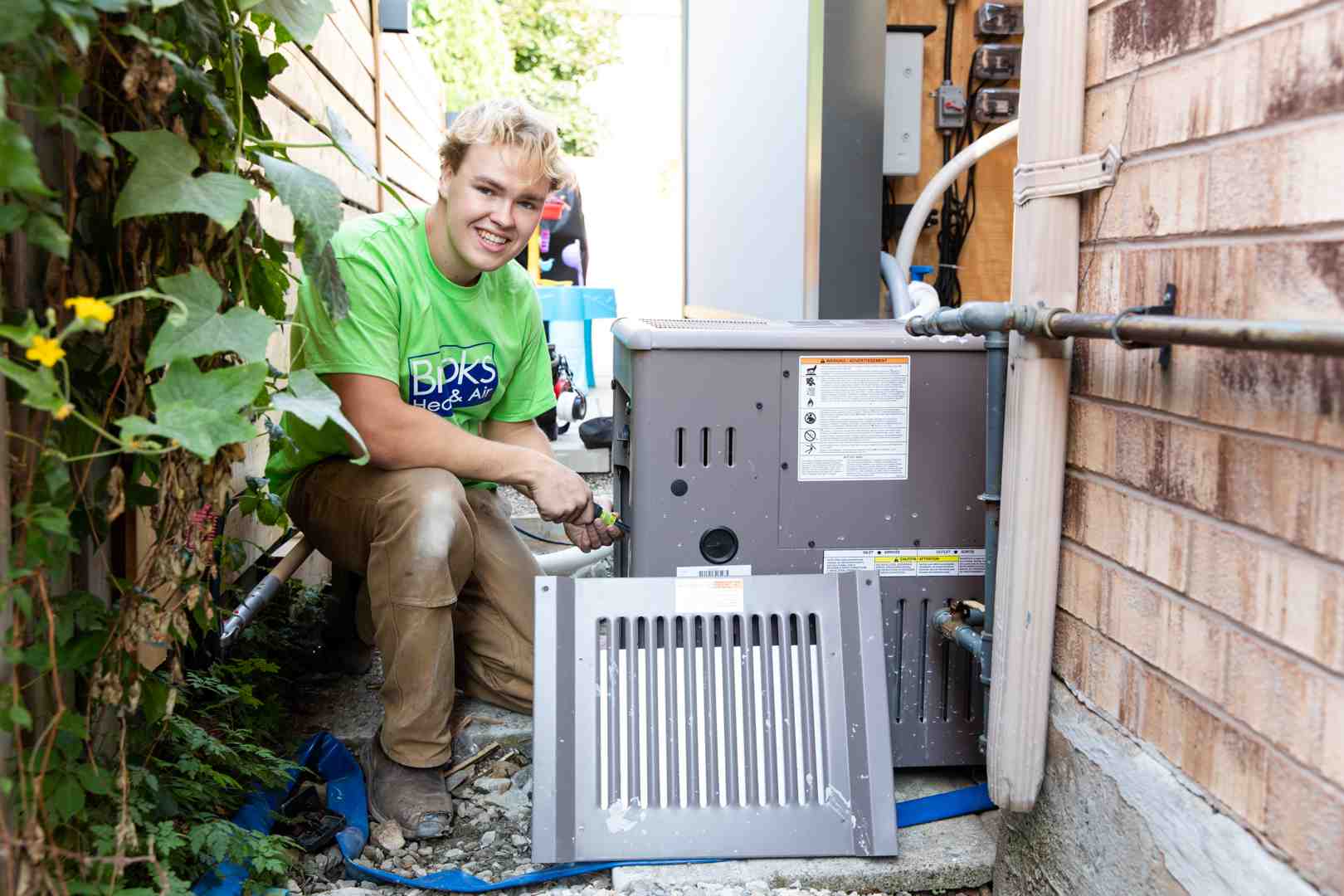 an HVAC technician performing maintenance on an outdoor AC unit - annual hvac maintenance ontario
