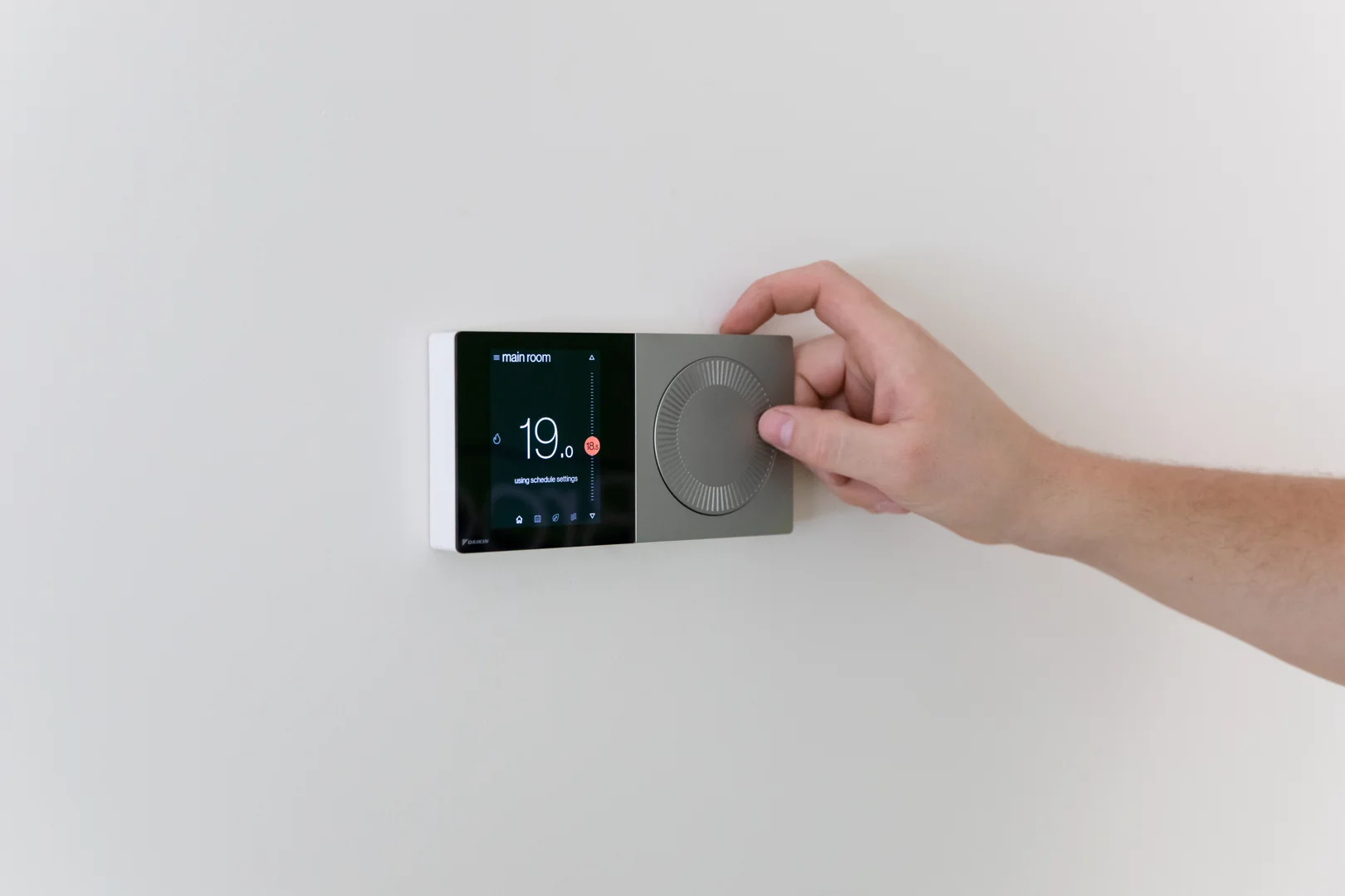 homeowner adjusting a modern smart thermostat in their living room homeowner adjusting a modern smart thermostat in their living room