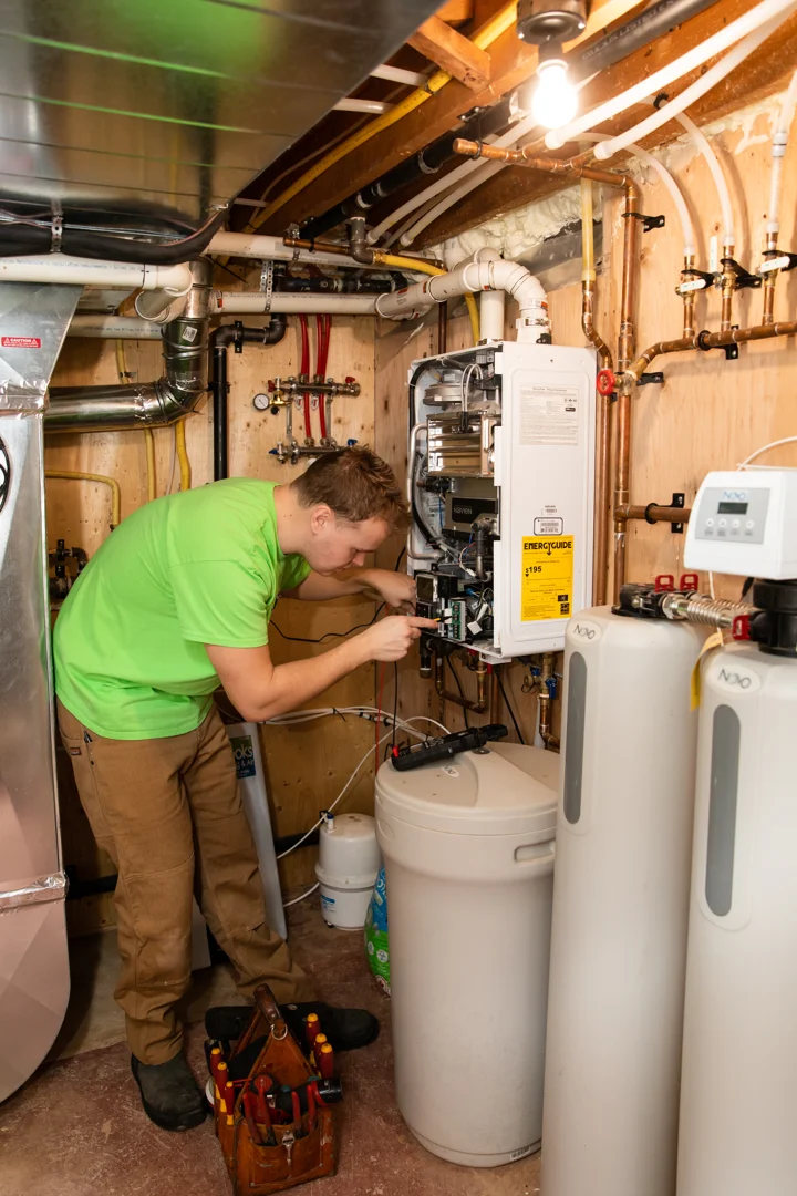 A homeowner checking for signs of water heater failure in a clean basement utility room