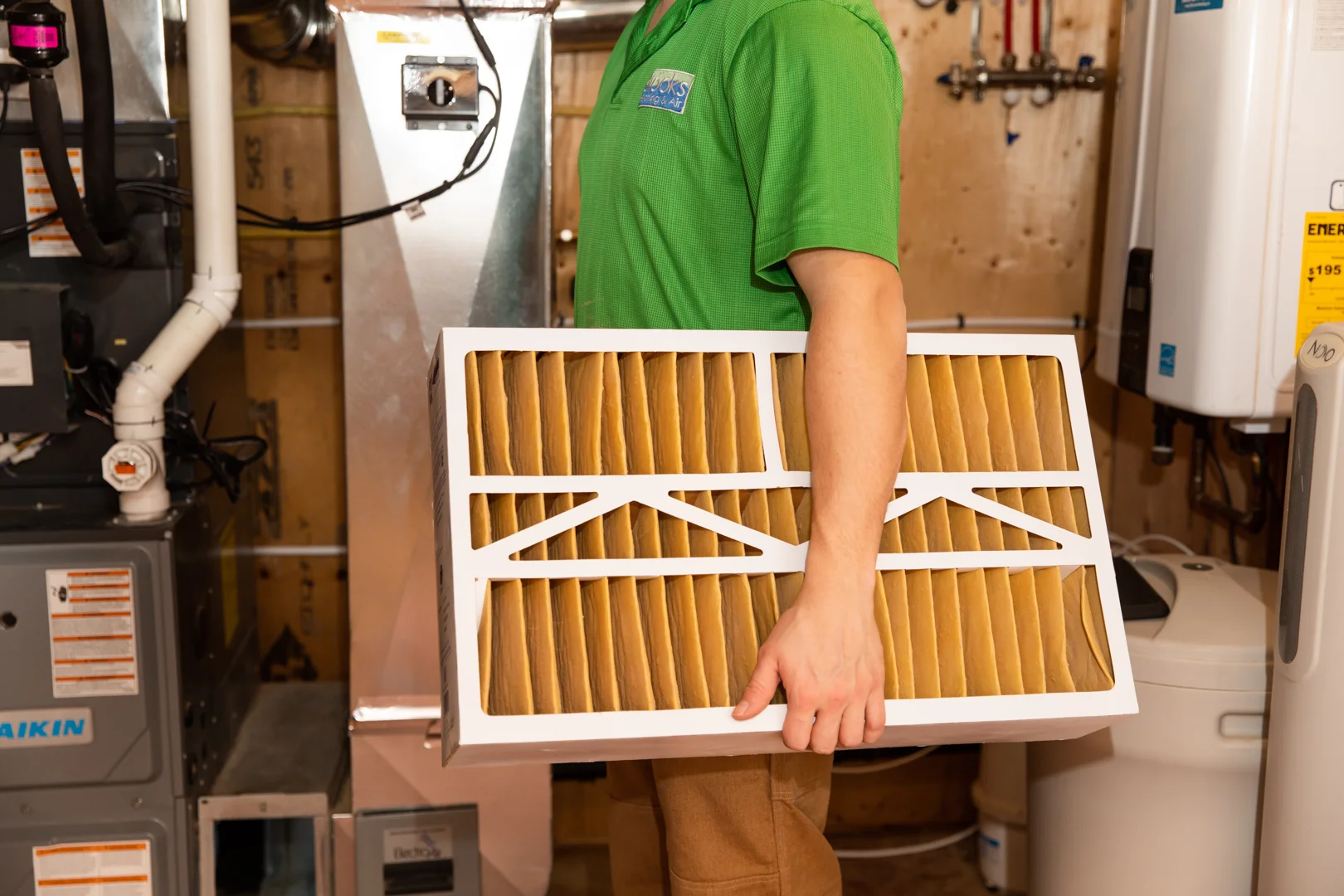 homeowner inspecting a furnace air filter in a clean utility room