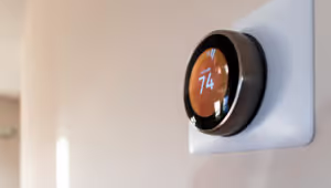 Smart thermostat mounted on a wall, displaying temperature settings and controls.
