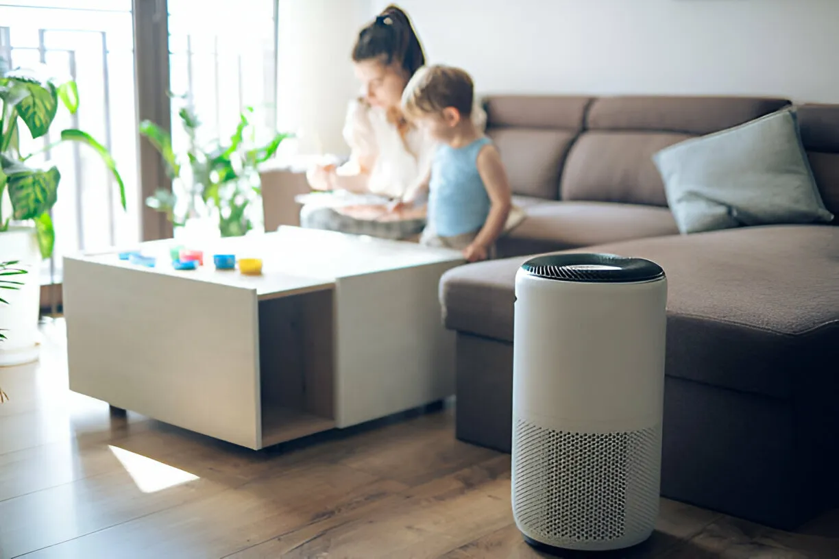 Air purifier in living room with caregiver and child playing in background
