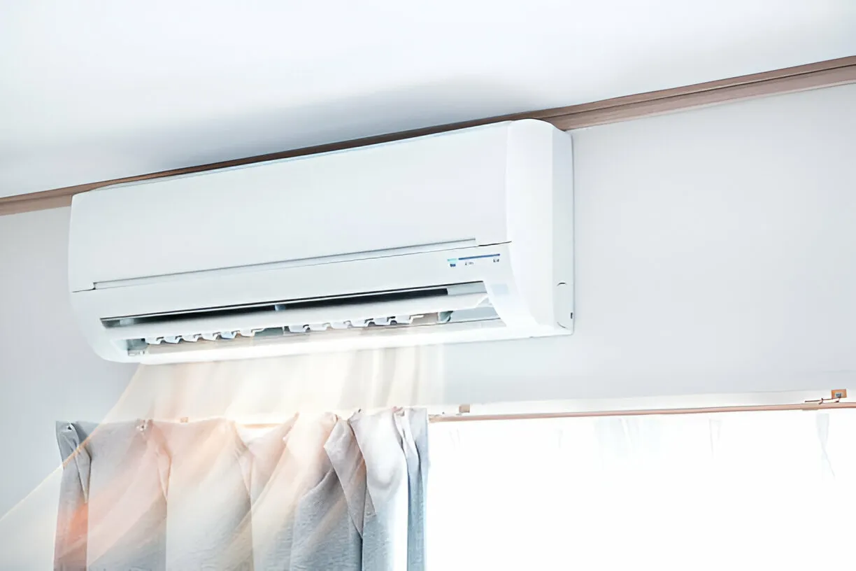 White wall-mounted air conditioner above soft pastel curtains